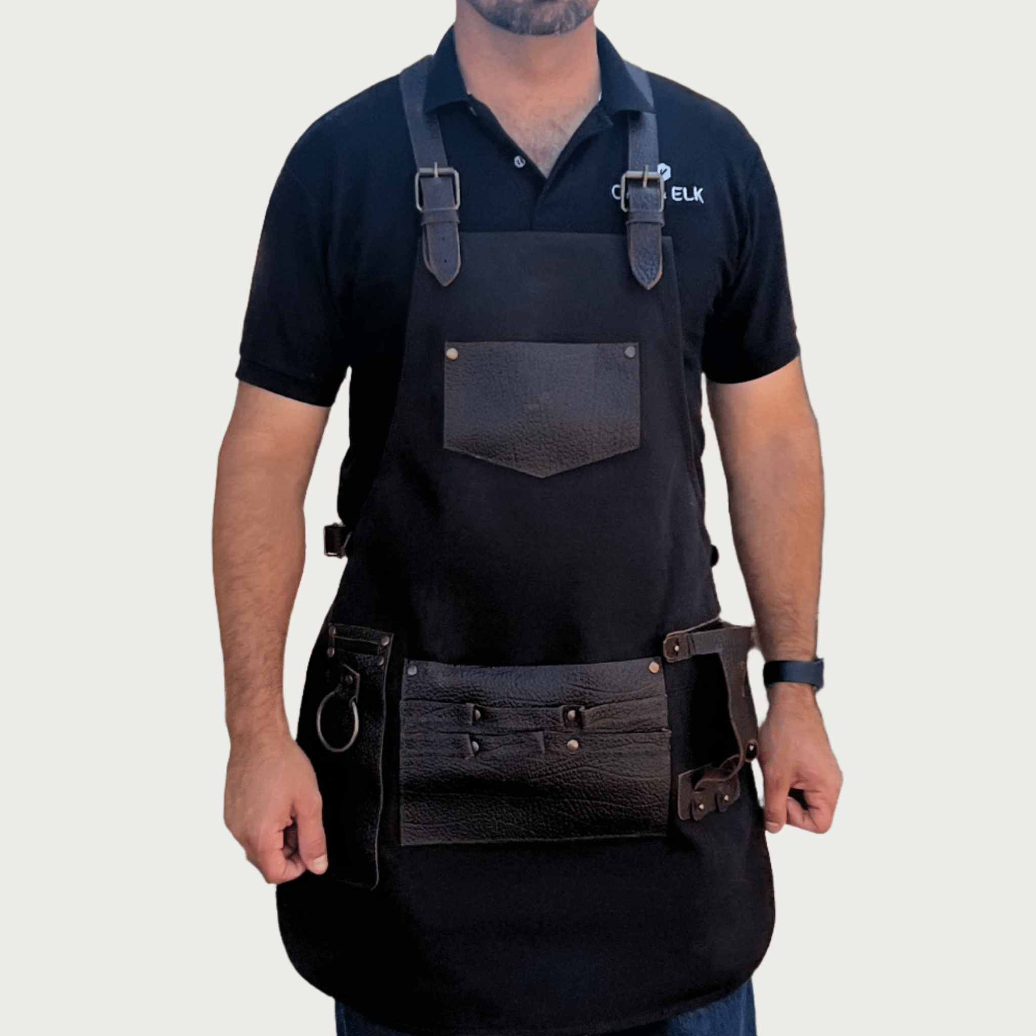 Black canvas and leather workshop apron with adjustable straps and tool pockets, suited to blacksmithing and forge work, by OAK & ELK