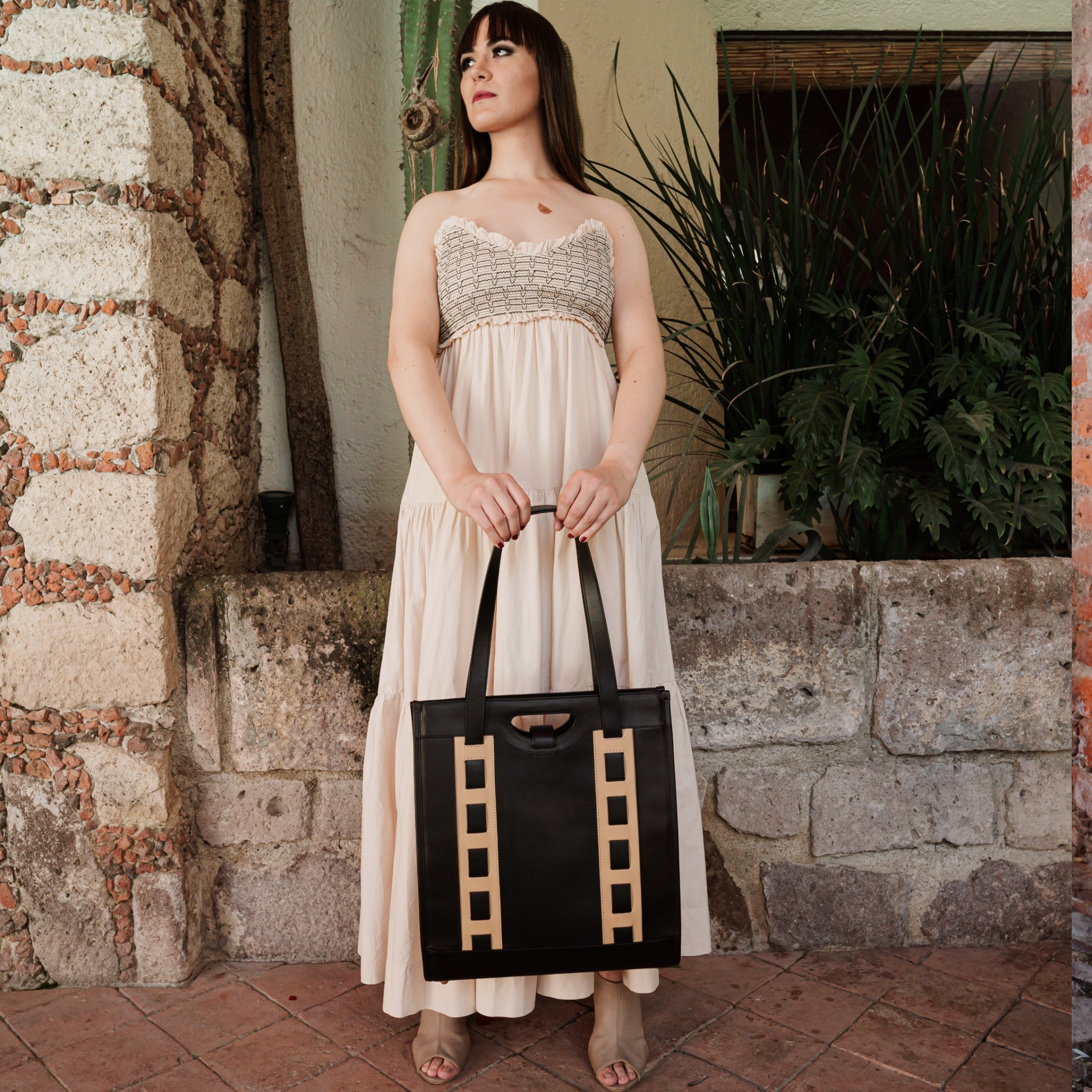 Tote bag with handwoven cane body and black leather trim, open top, structured shape, and dual handles — artisan and elegant.