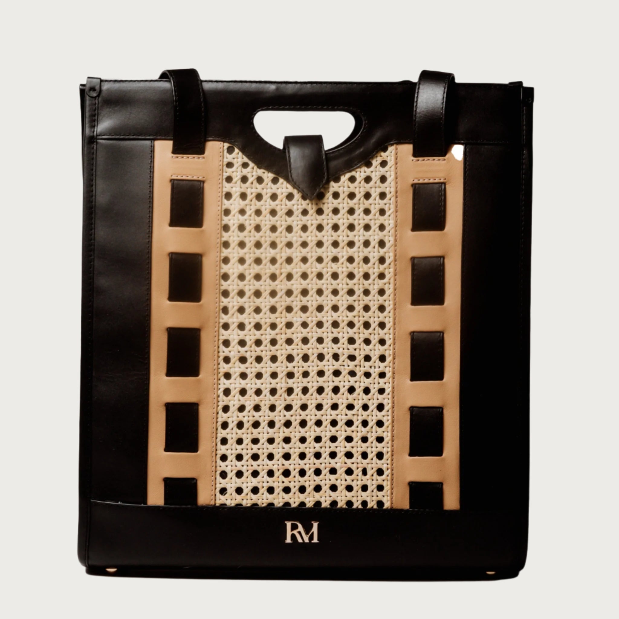 Tote bag with handwoven cane body and black leather trim, open top, structured shape, and dual handles — artisan and elegant.