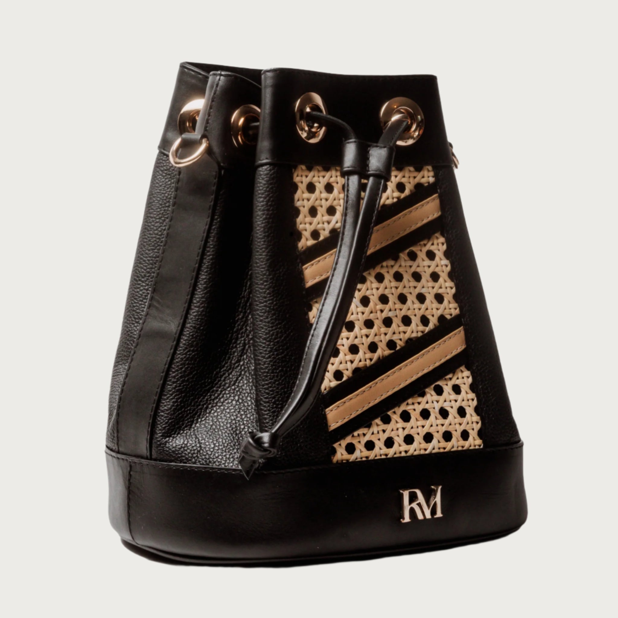 Wicker and black leather bucket bag with drawstring closure, gold hardware, inner lining, and artisan-made woven structure.