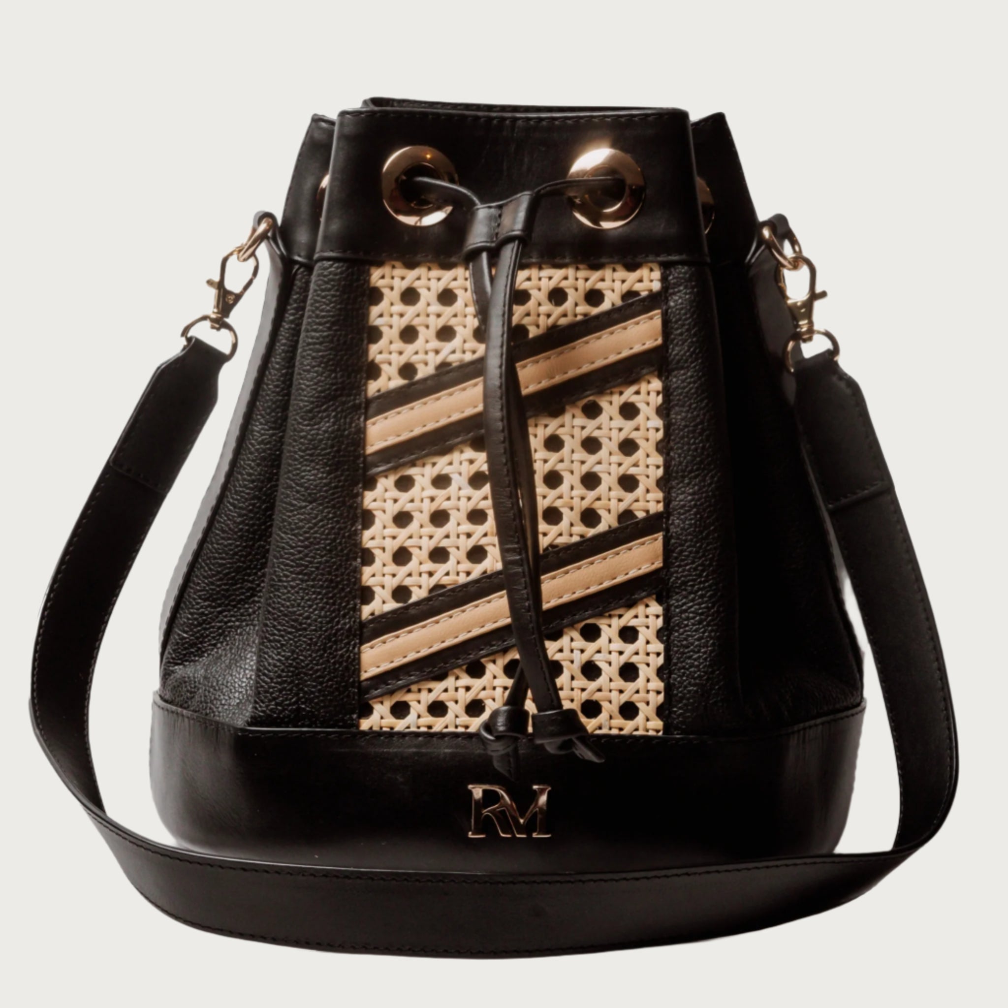 Wicker and black leather bucket bag with drawstring closure, gold hardware, inner lining, and artisan-made woven structure.