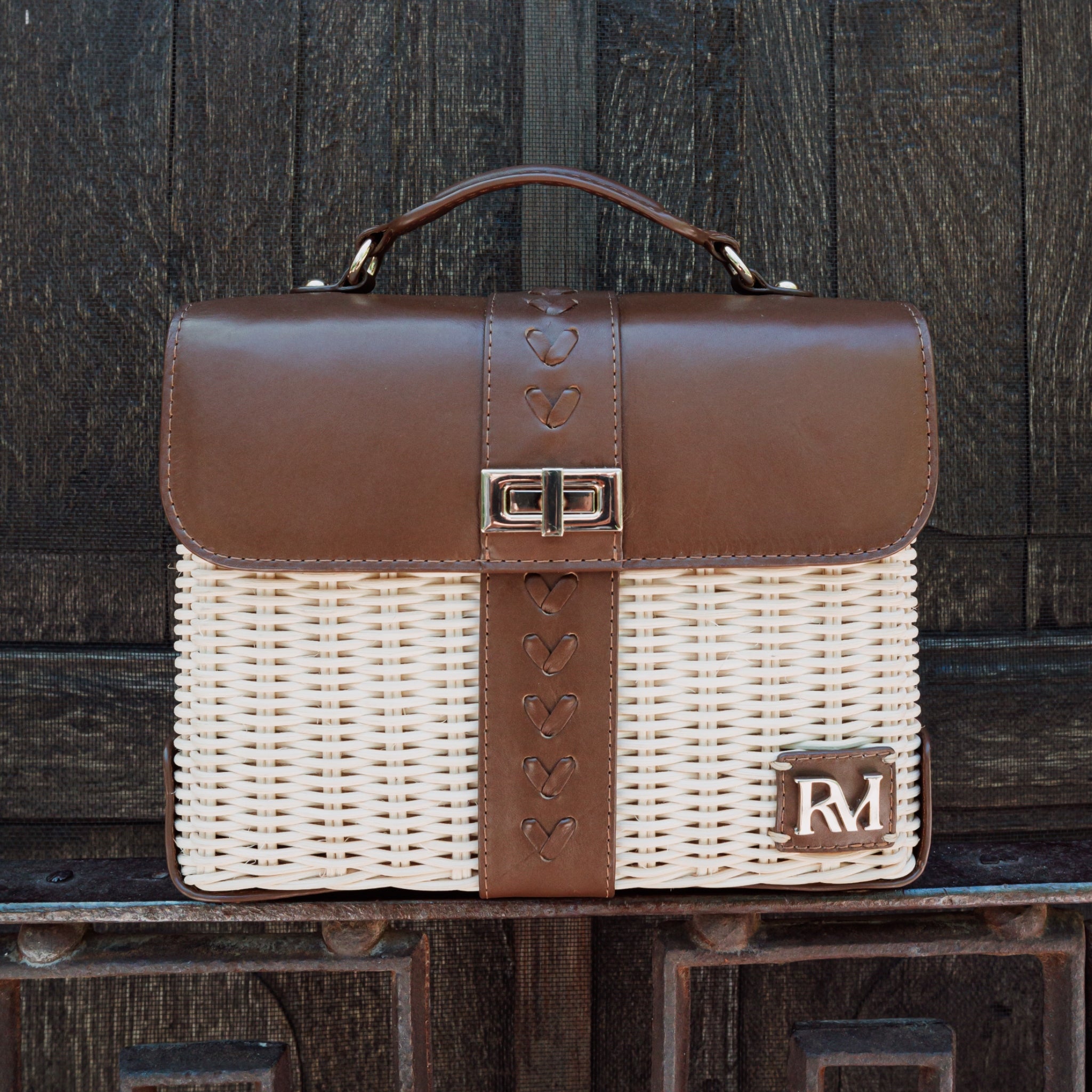 Structured handbag with woven rattan body, leather flap and trim, gold hardware, and top handle — elegant and artisan-crafted