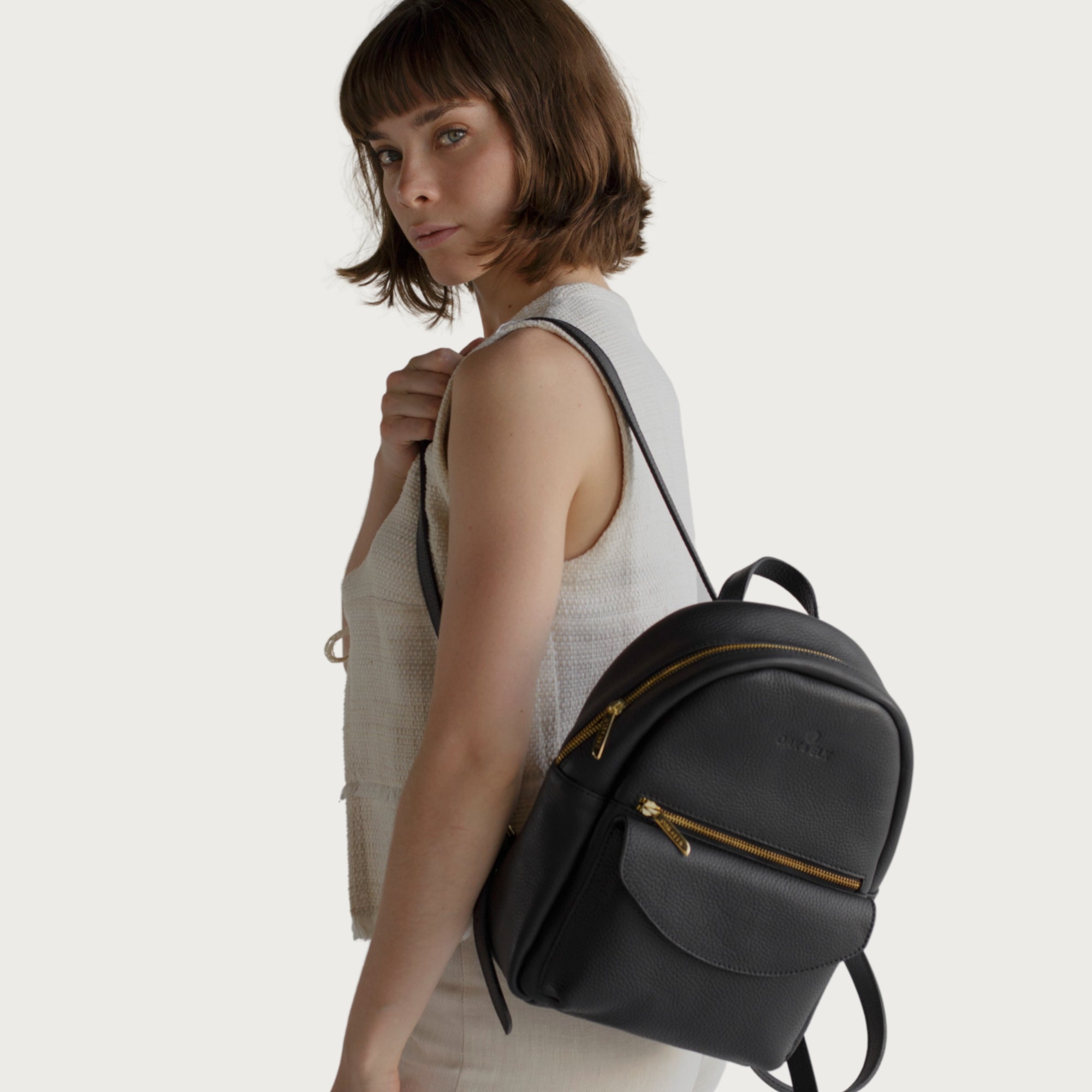 Leather backpack with smooth finish, adjustable straps, front zipper pocket, and gold hardware – Emma by OAK & ELK.