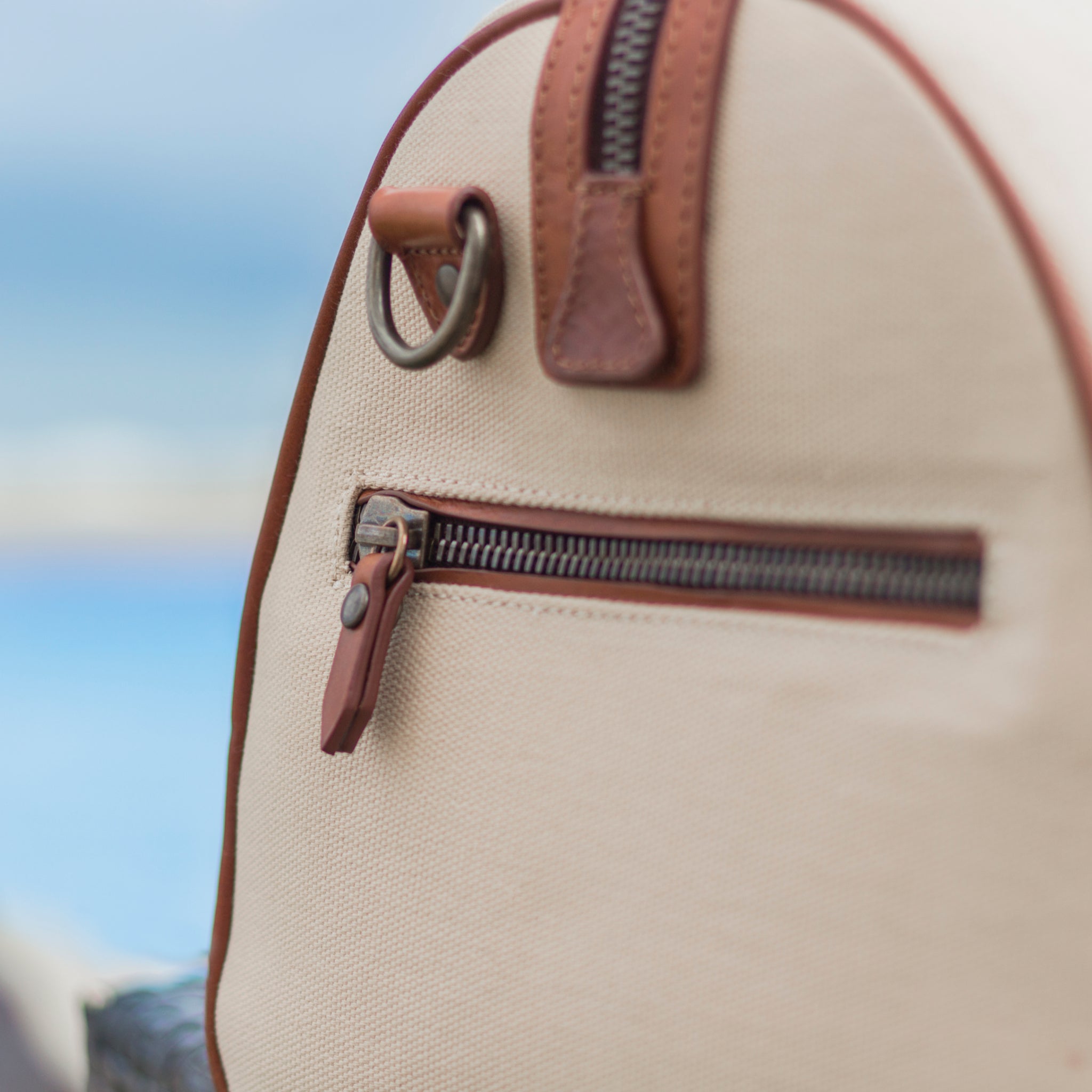 Large canvas and leather duffel bag with top handles, adjustable shoulder strap, leather trim, and zip closure, for travel