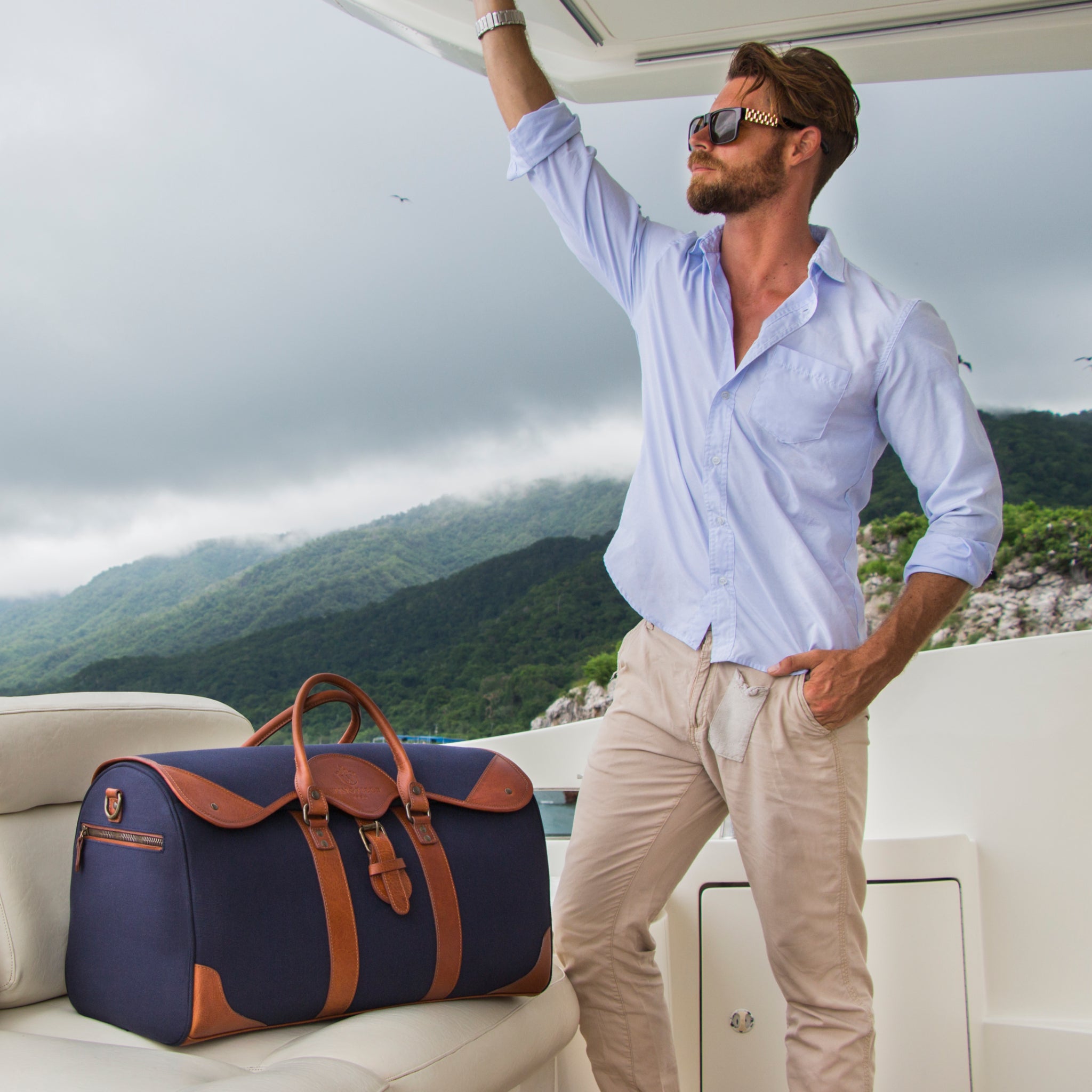 Large canvas and leather duffel bag with top handles, adjustable shoulder strap, leather trim, and zip closure, for travel