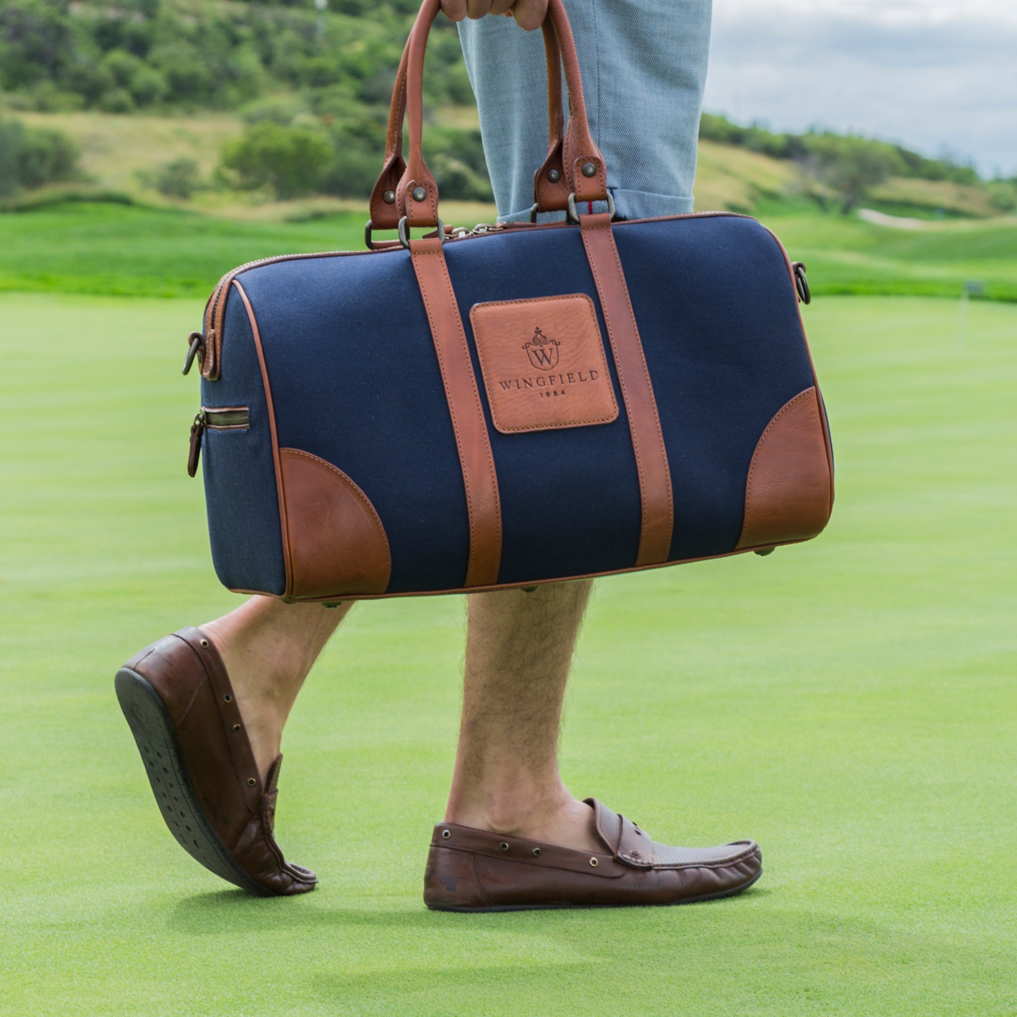 Compact canvas and leather duffel bag with top handles, adjustable shoulder strap, leather accents, zip closure travel ready