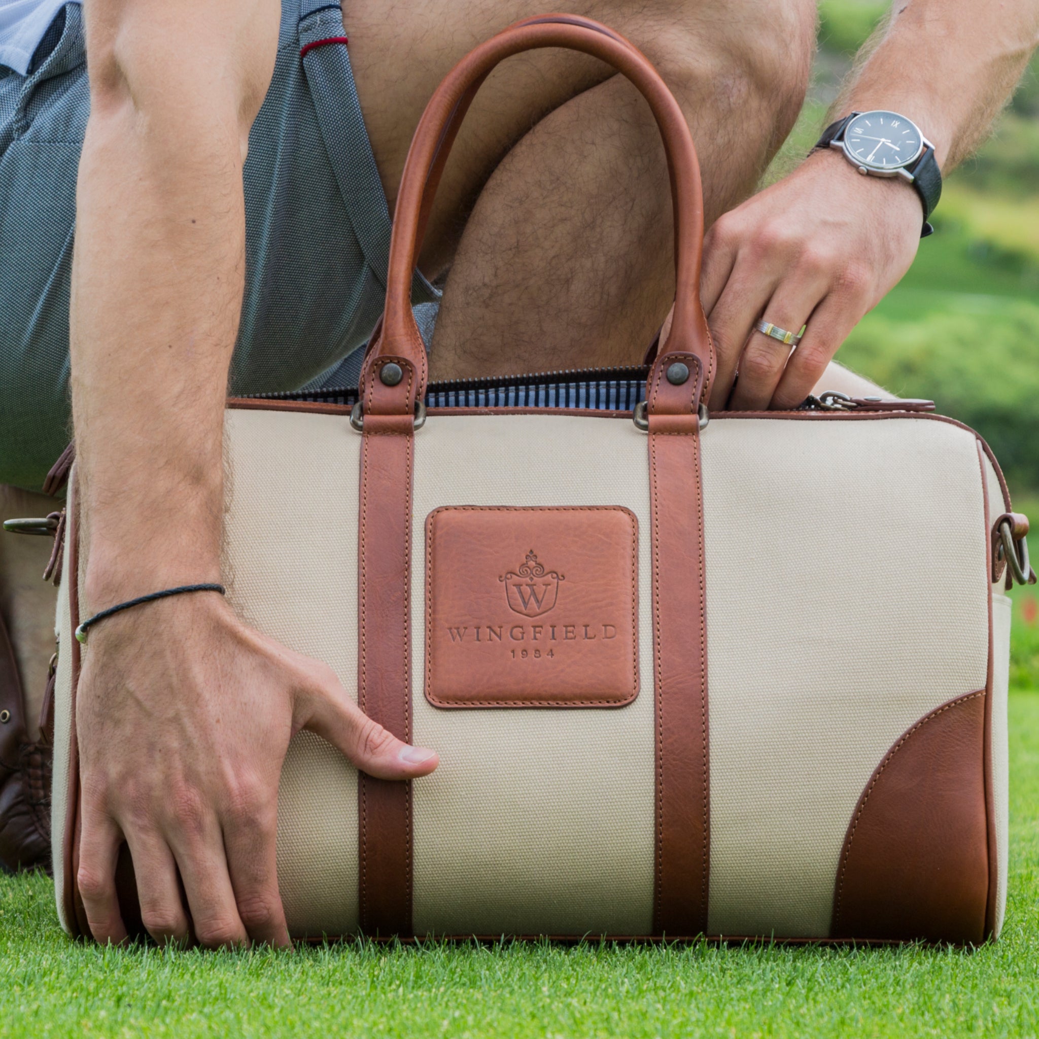 Compact canvas and leather duffel bag with top handles, adjustable shoulder strap, leather accents, zip closure travel ready