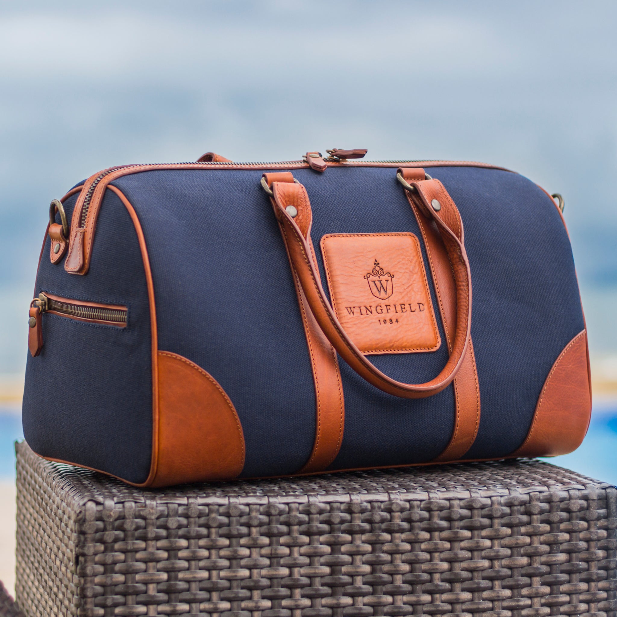 Compact canvas and leather duffel bag with top handles, adjustable shoulder strap, leather accents, zip closure travel ready