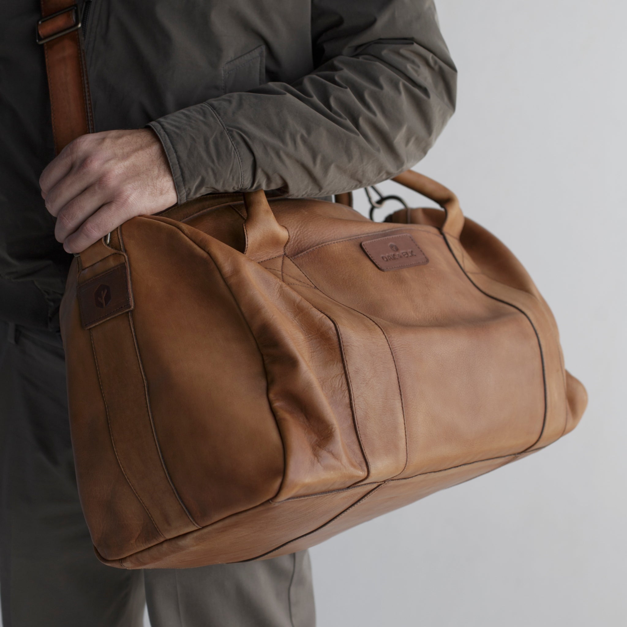 Leather duffel bag made of top-grain leather with smooth zipper, structured body, interior pockets, and adjustable strap