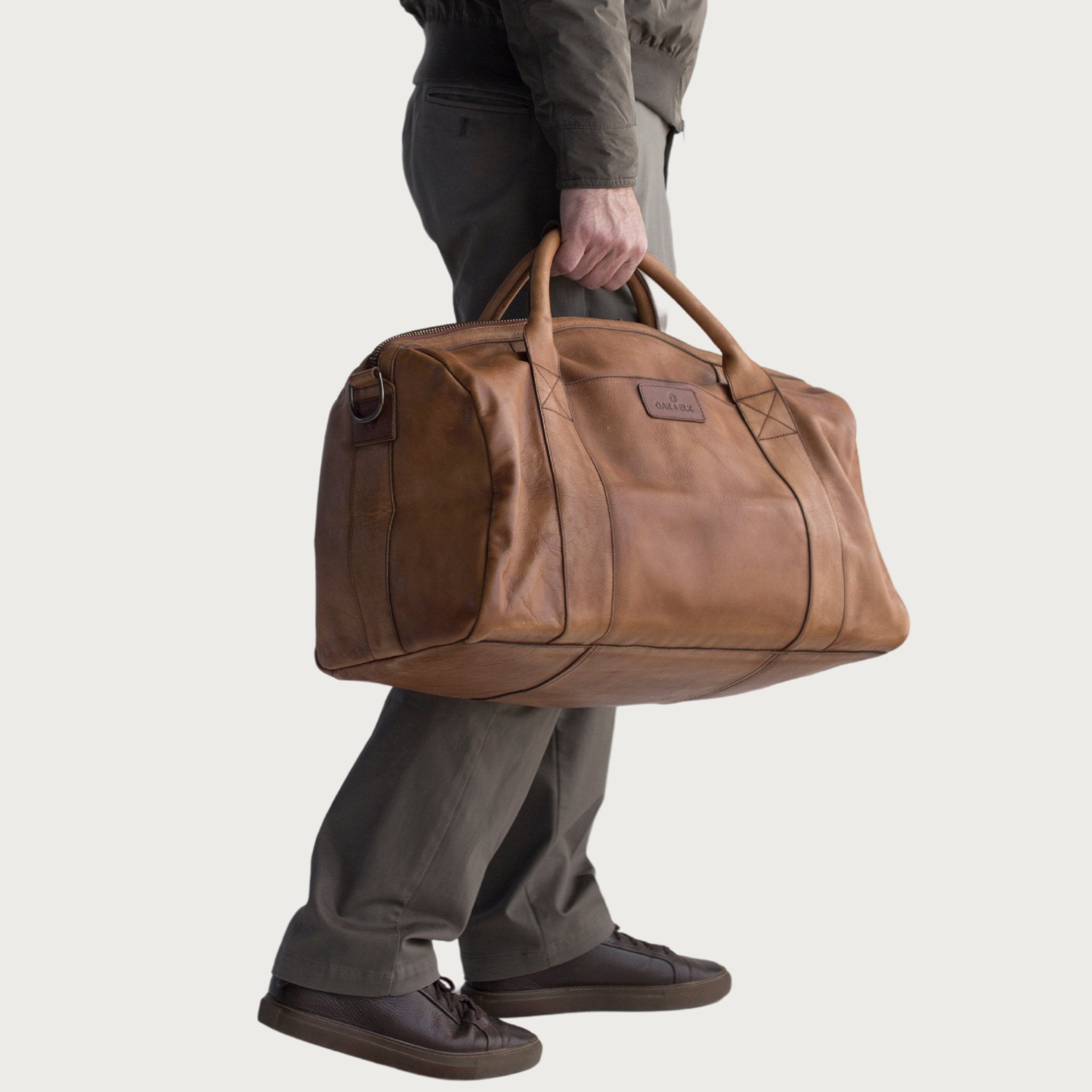 Leather duffel bag made of top-grain leather with smooth zipper, structured body, interior pockets, and adjustable strap