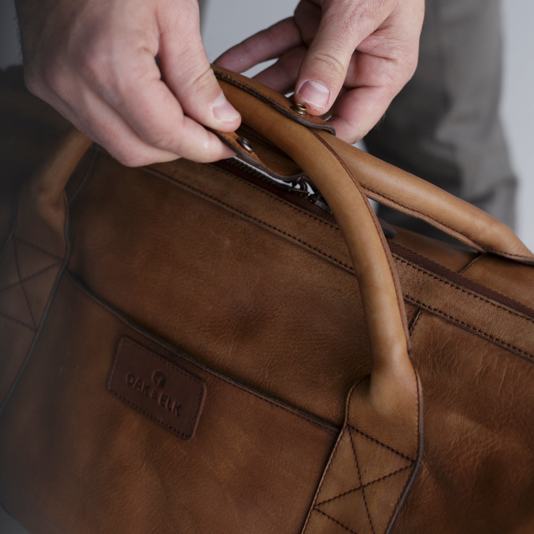 Leather duffel bag made of top-grain leather with smooth zipper, structured body, interior pockets, and adjustable strap