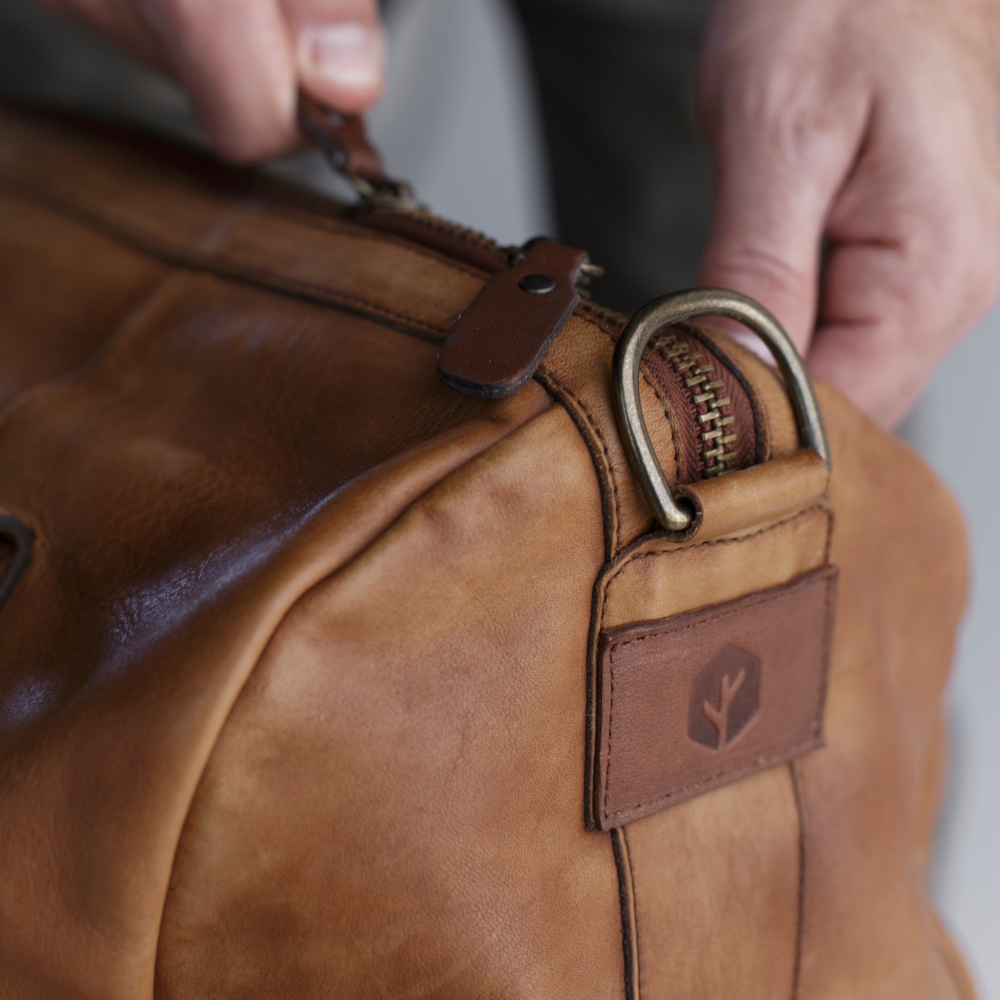 Leather duffel bag made of top-grain leather with smooth zipper, structured body, interior pockets, and adjustable strap