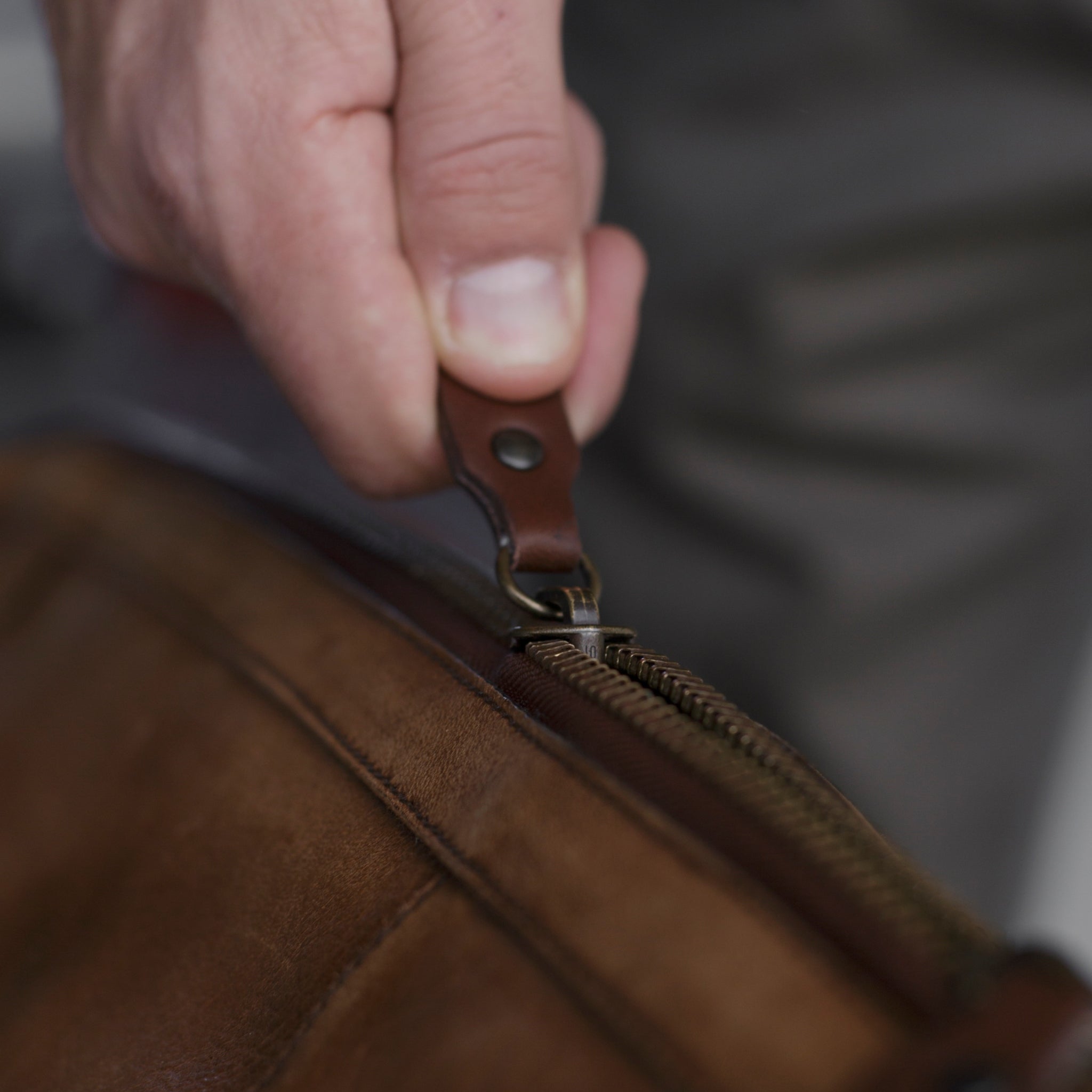 Leather duffel bag made of top-grain leather with smooth zipper, structured body, interior pockets, and adjustable strap