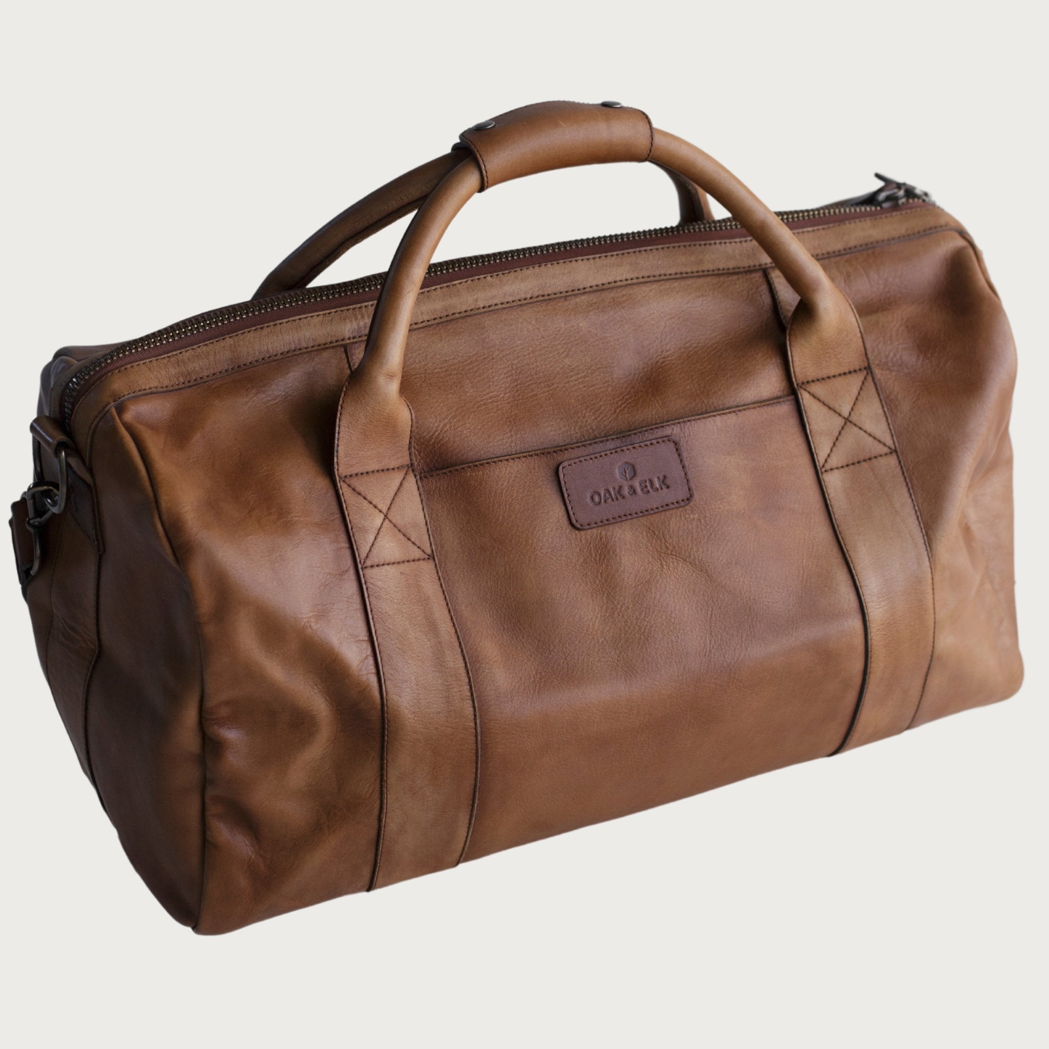 Leather duffel bag made of top-grain leather with smooth zipper, structured body, interior pockets, and adjustable strap