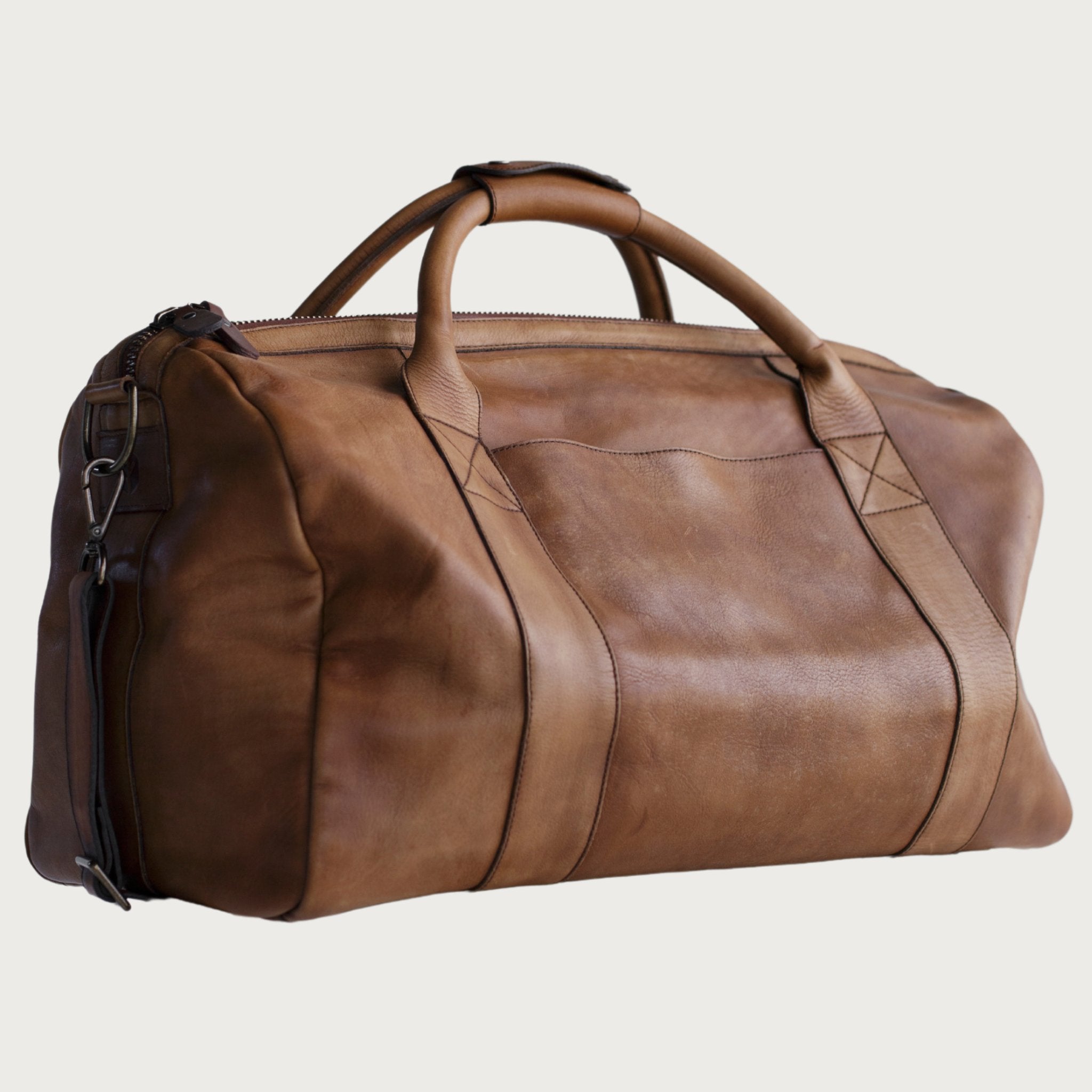 Leather duffel bag made of top-grain leather with smooth zipper, structured body, interior pockets, and adjustable strap