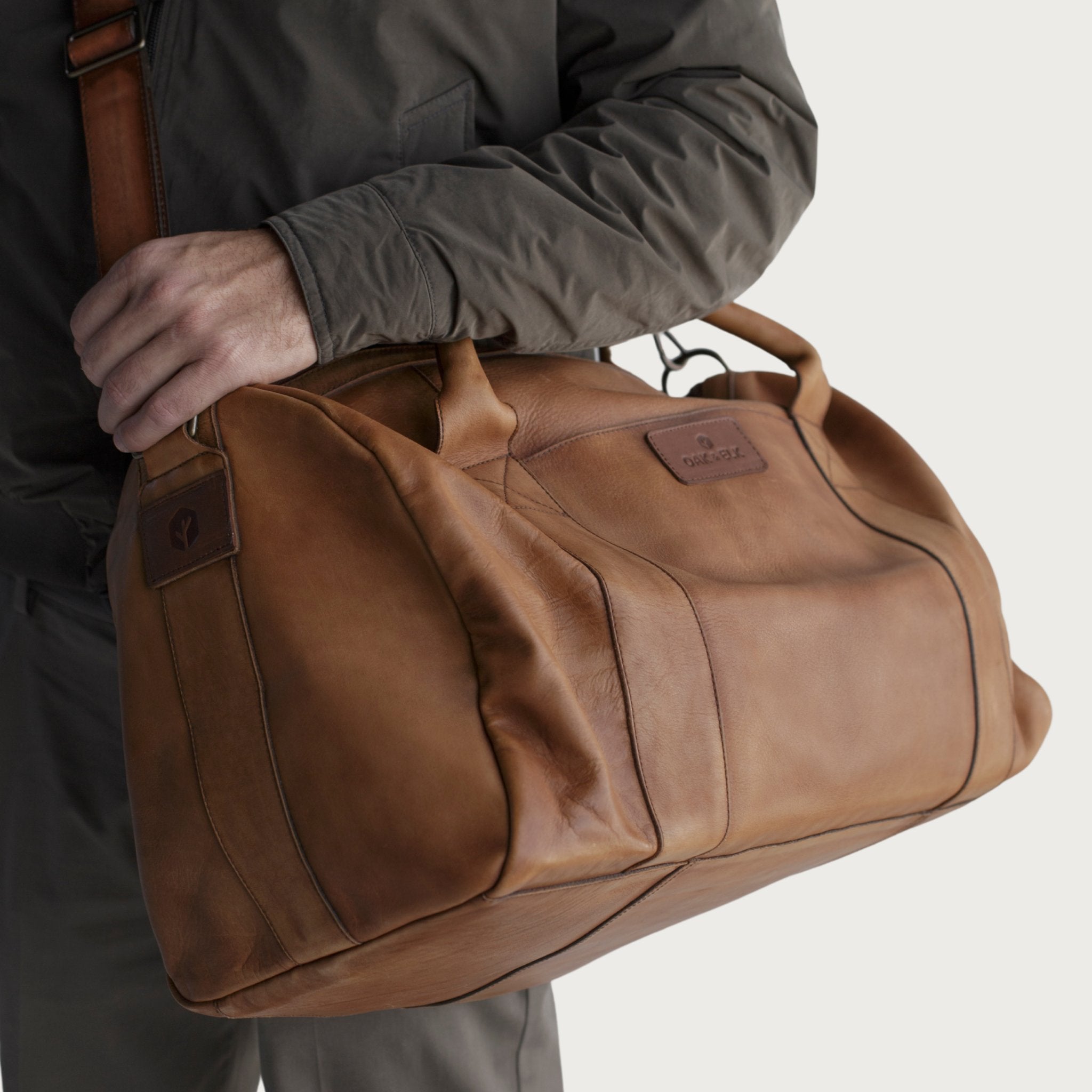 Leather duffel bag made of top-grain leather with smooth zipper, structured body, interior pockets, and adjustable strap