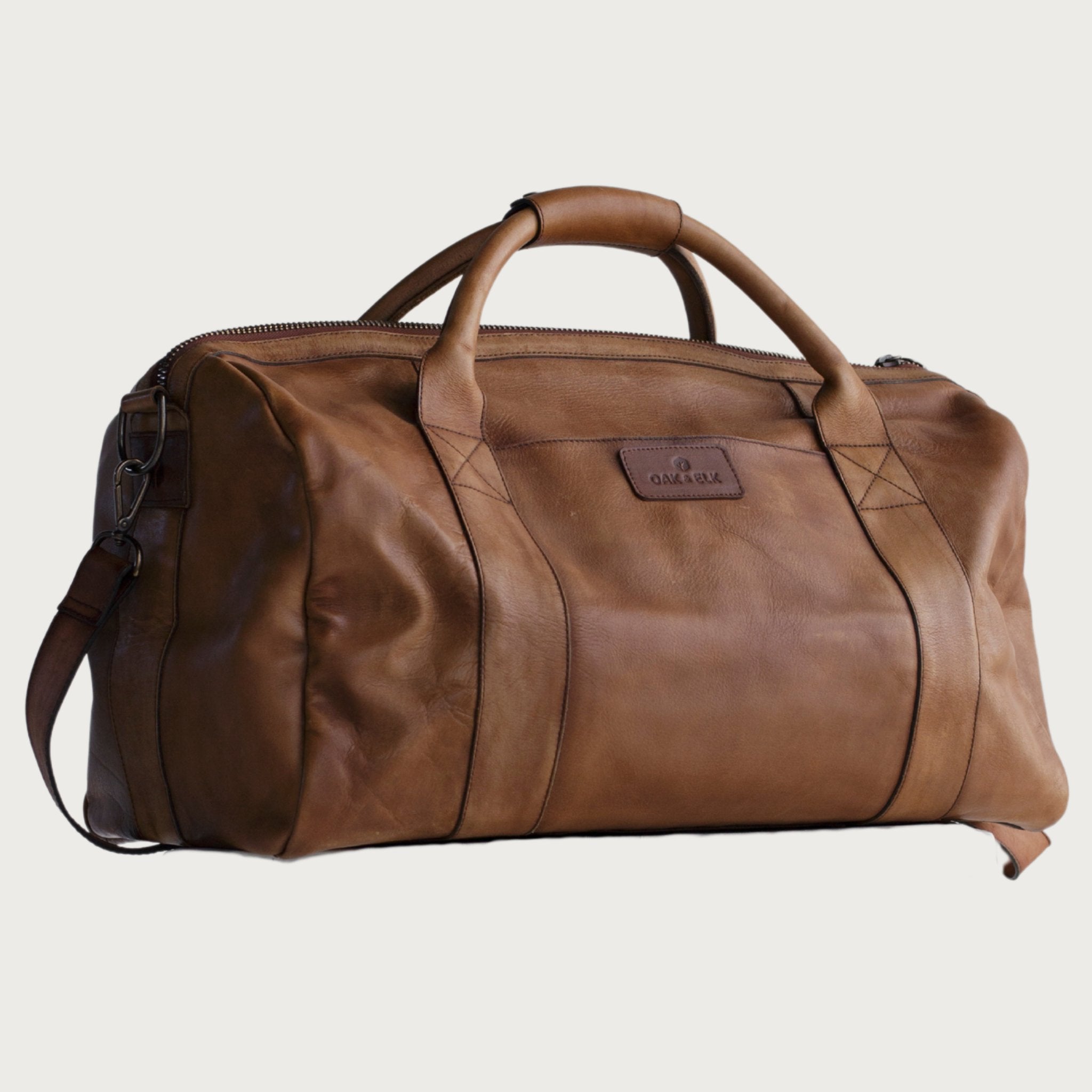 Leather duffel bag made of top-grain leather with smooth zipper, structured body, interior pockets, and adjustable strap