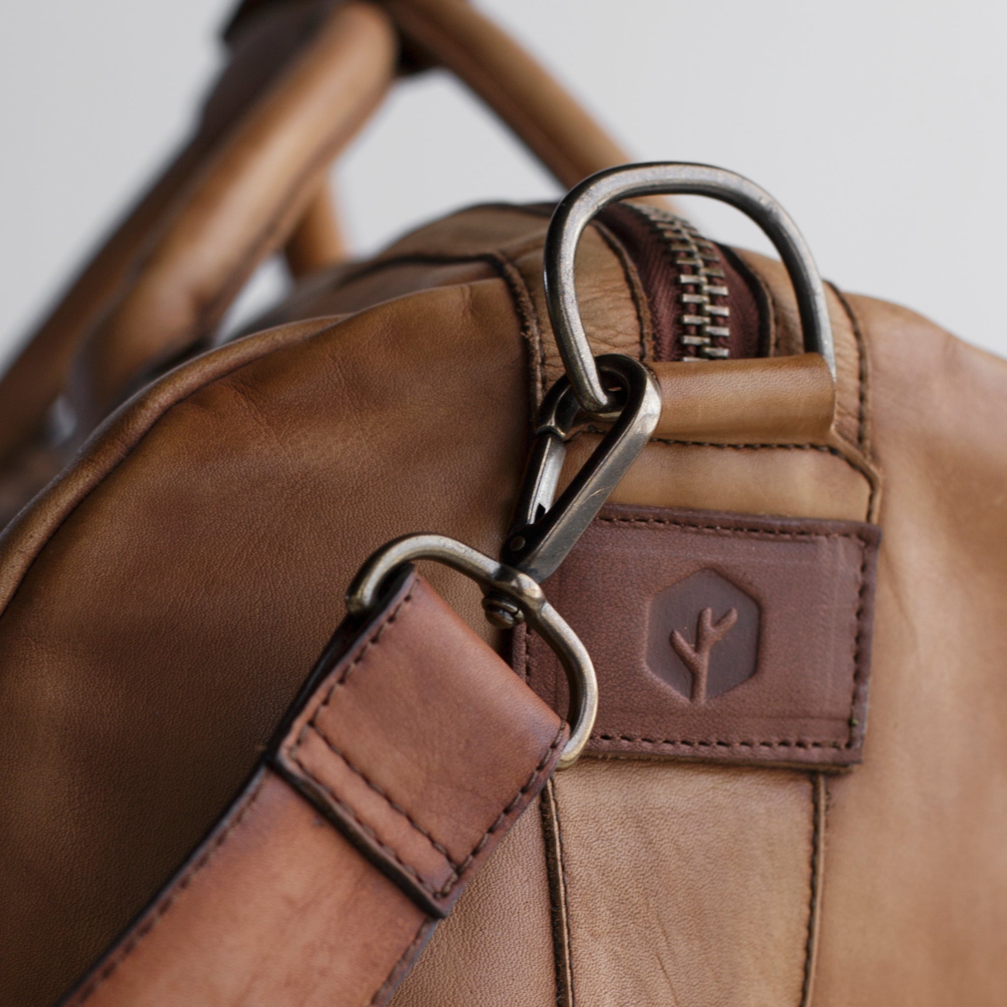 Leather duffel bag made of top-grain leather with smooth zipper, structured body, interior pockets, and adjustable strap