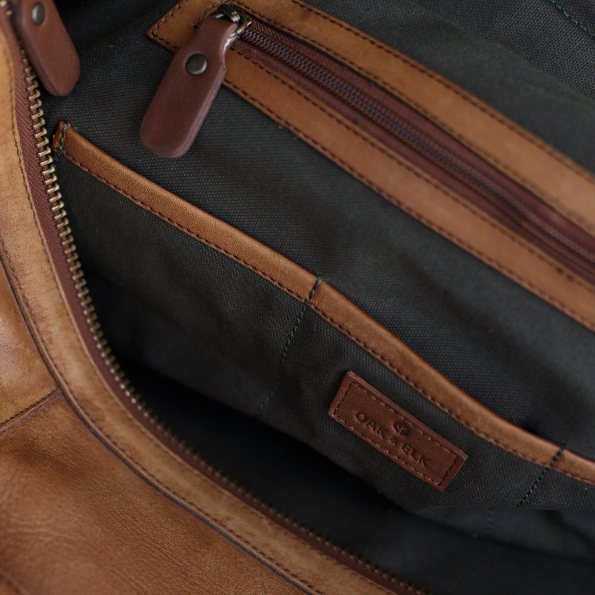 Leather duffel bag made of top-grain leather with smooth zipper, structured body, interior pockets, and adjustable strap