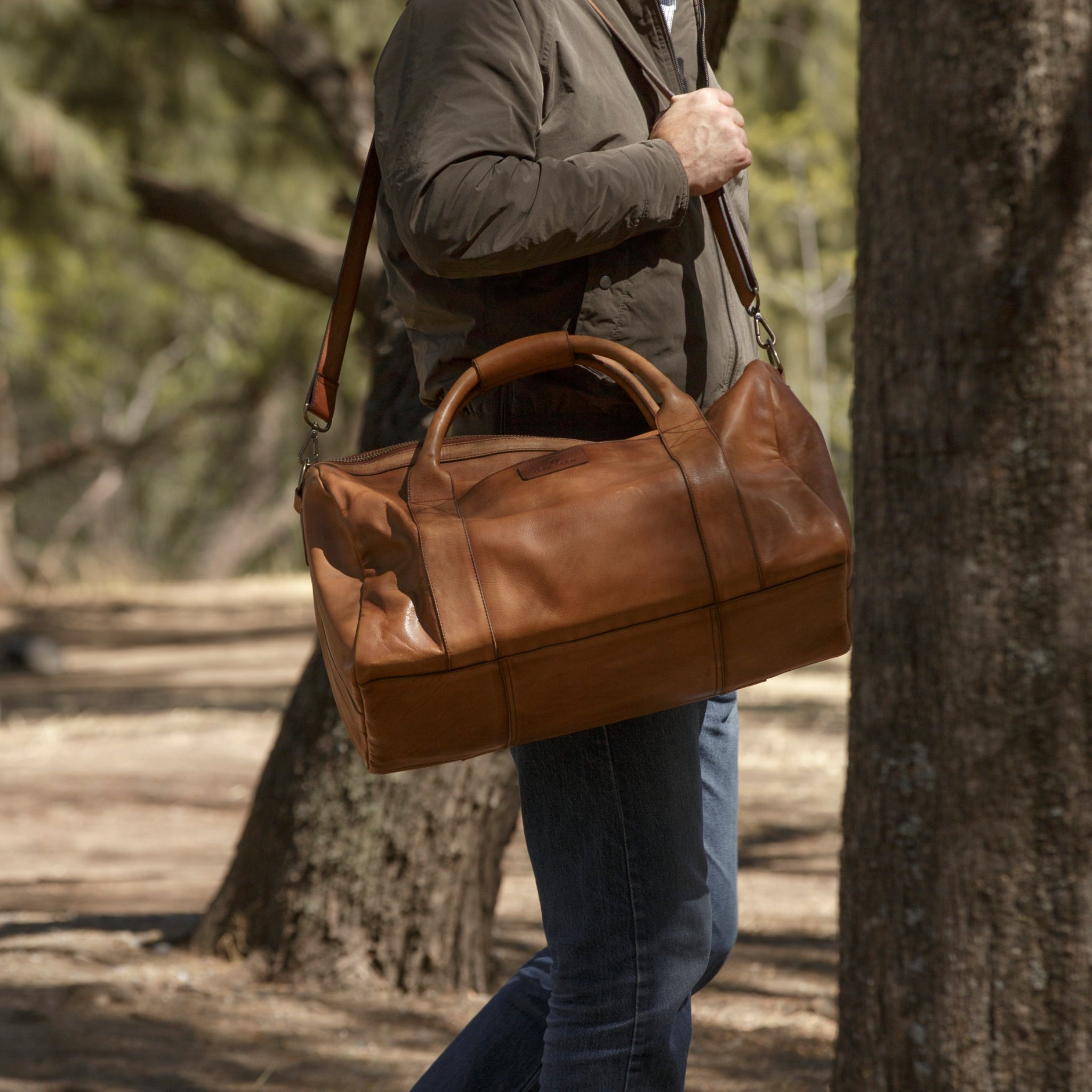 Leather duffel bag made of top-grain leather with smooth zipper, structured body, interior pockets, and adjustable strap