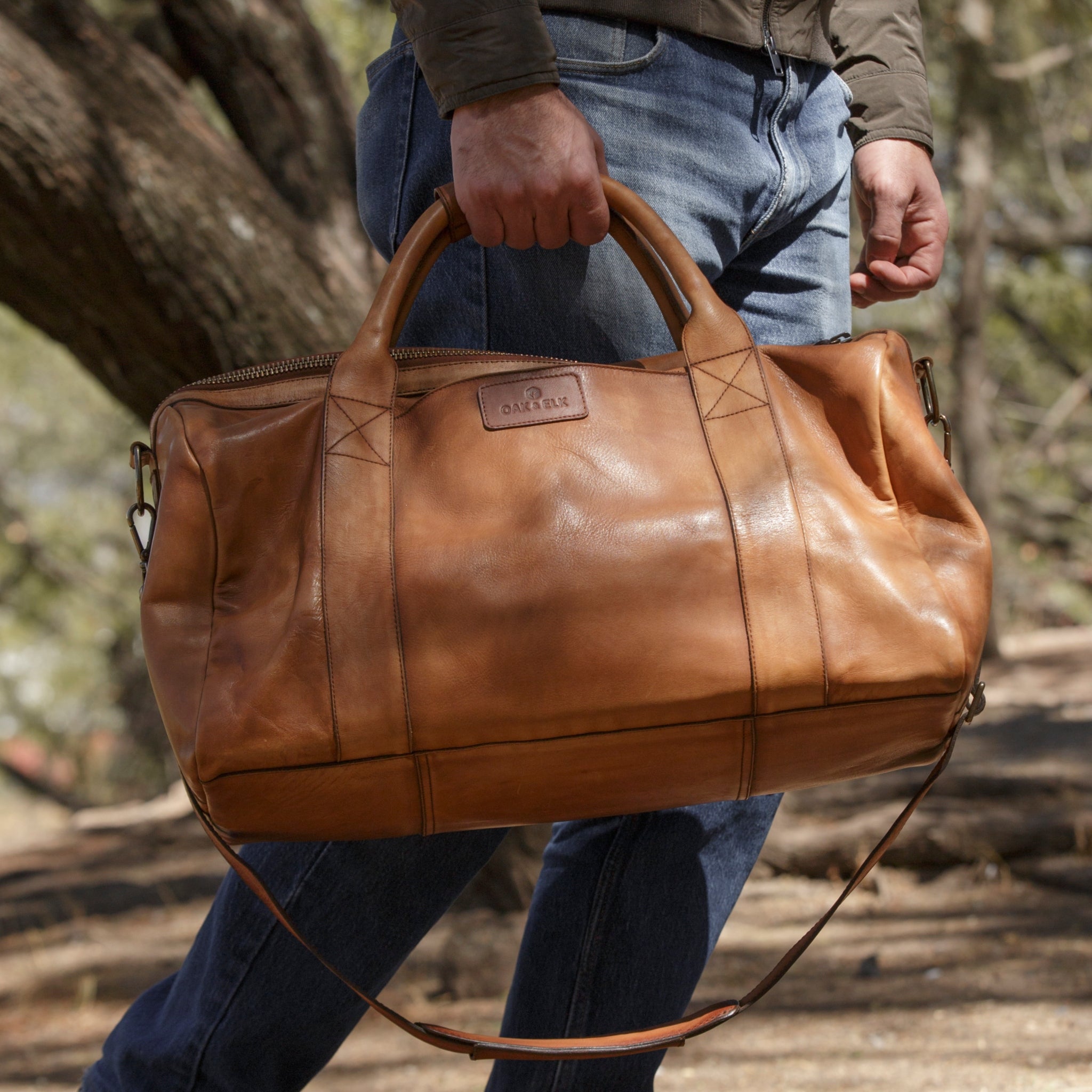 Leather duffel bag made of top-grain leather with smooth zipper, structured body, interior pockets, and adjustable strap