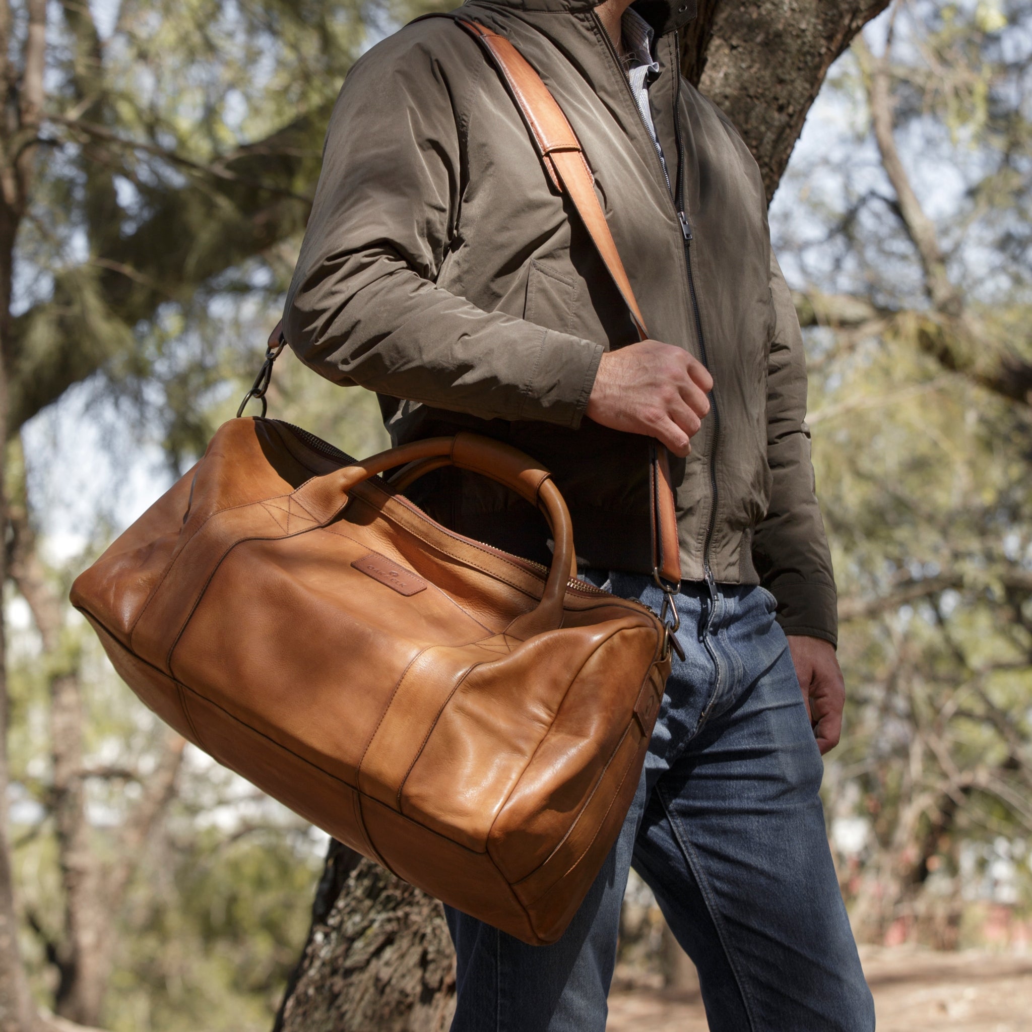 Leather duffel bag made of top-grain leather with smooth zipper, structured body, interior pockets, and adjustable strap