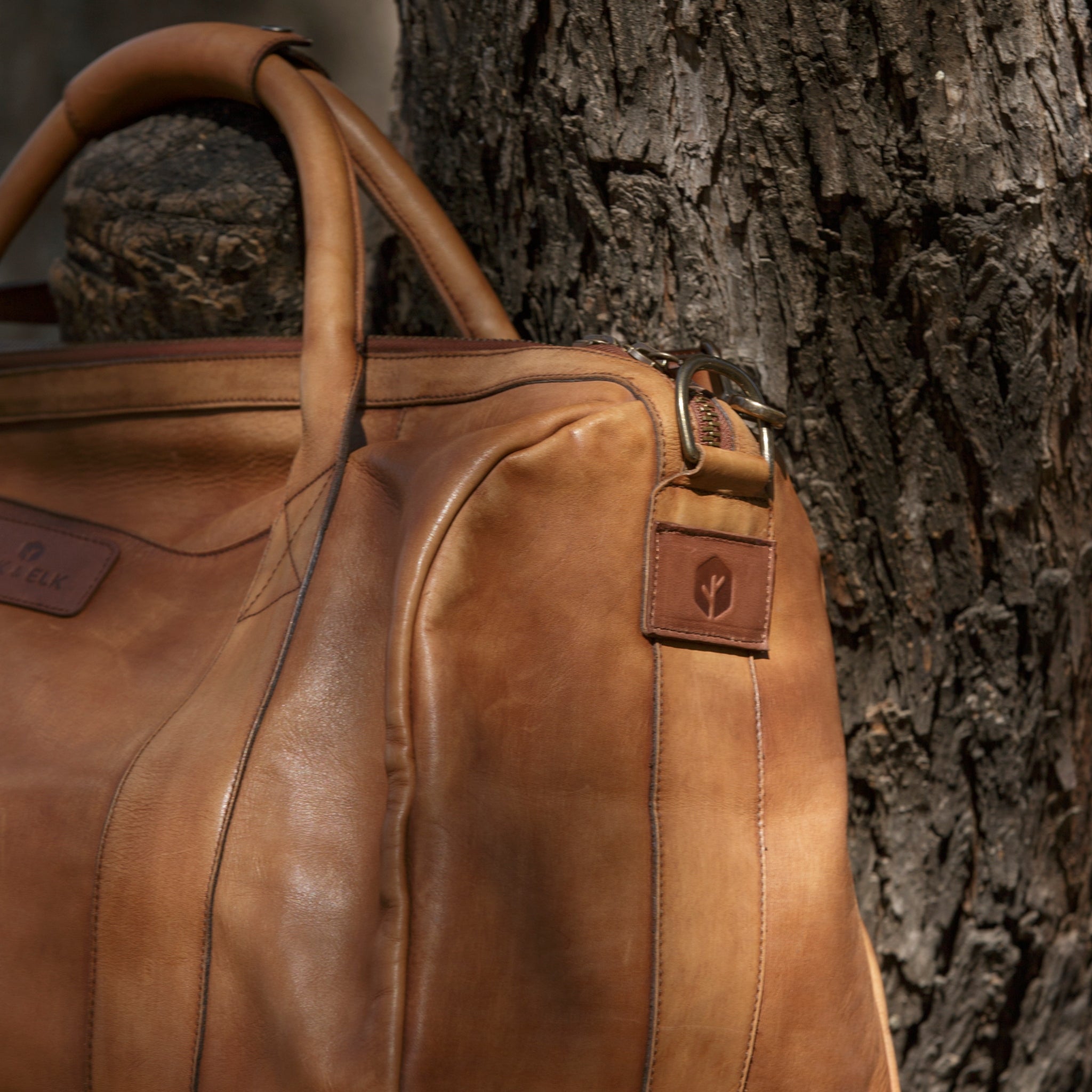Leather duffel bag made of top-grain leather with smooth zipper, structured body, interior pockets, and adjustable strap