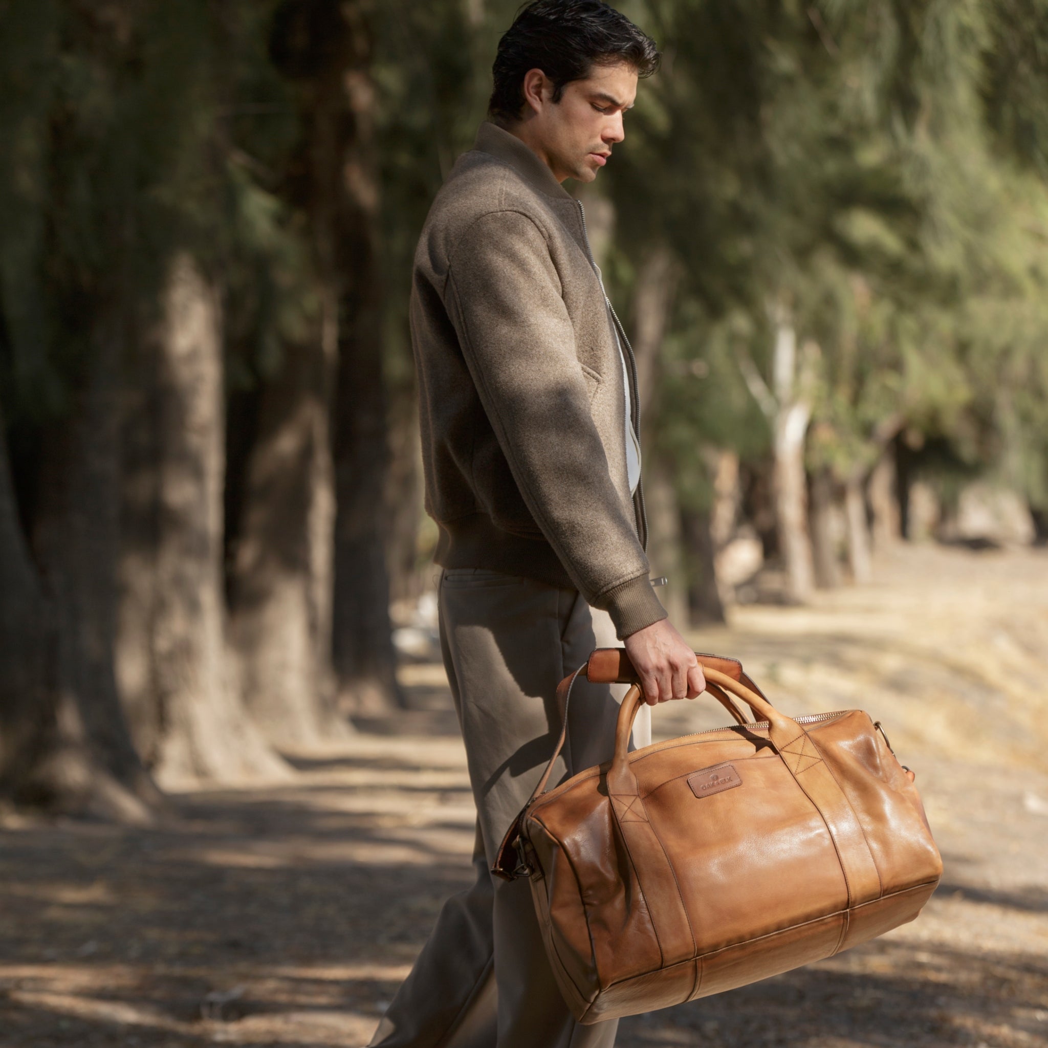 Leather duffel bag made of top-grain leather with smooth zipper, structured body, interior pockets, and adjustable strap