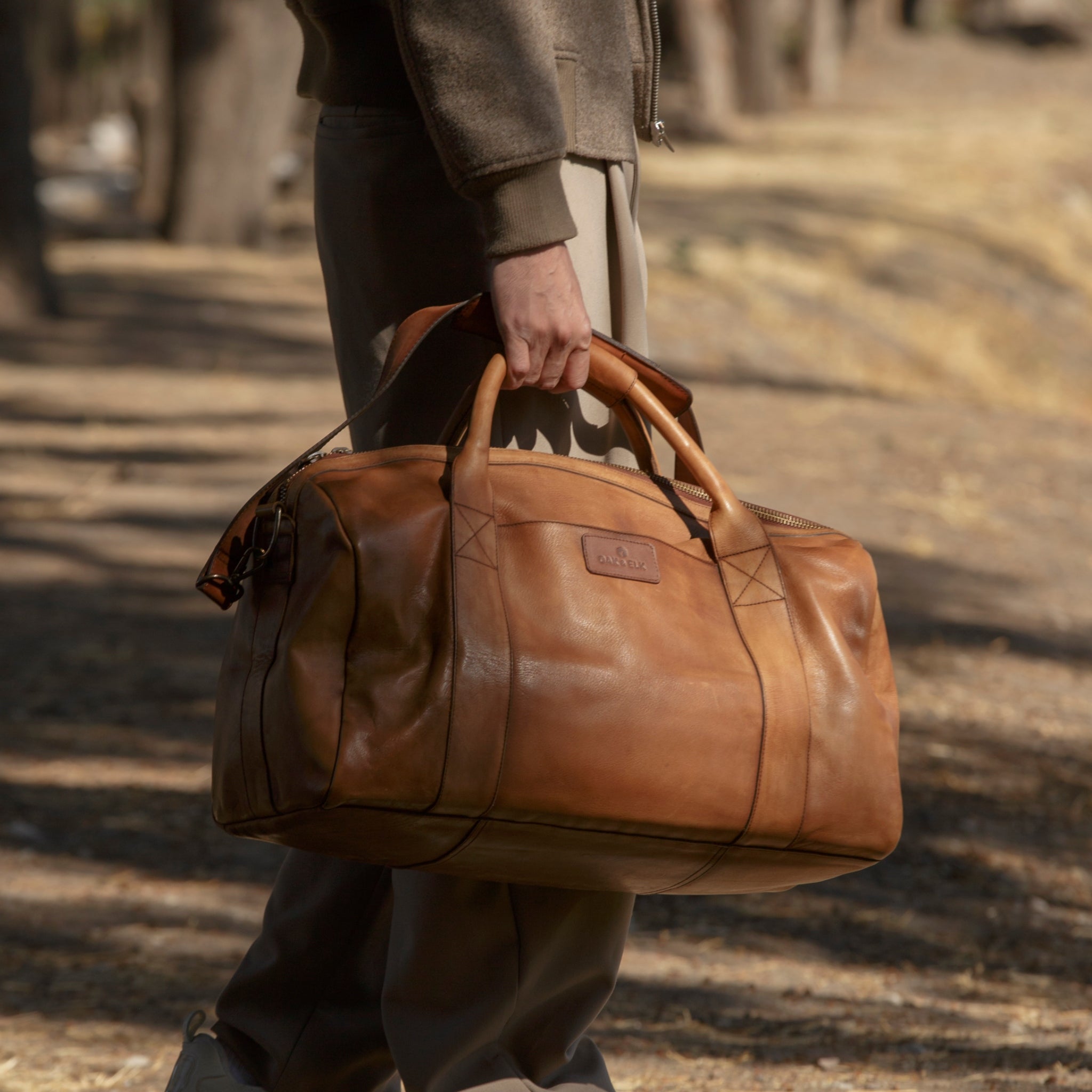 Leather duffel bag made of top-grain leather with smooth zipper, structured body, interior pockets, and adjustable strap
