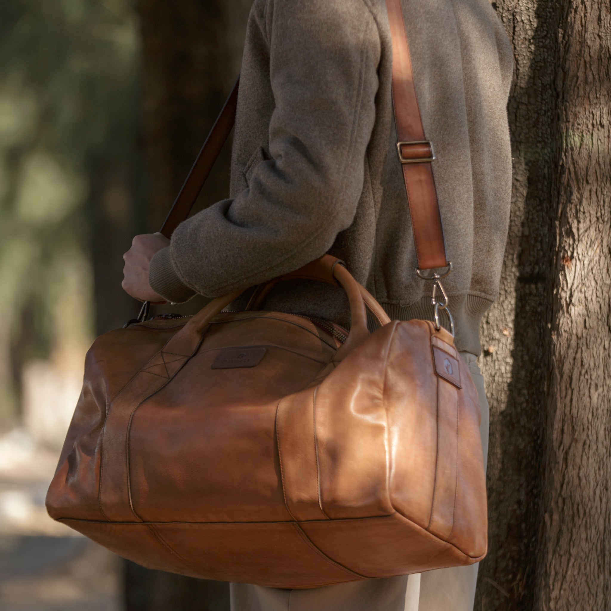 Leather duffel bag made of top-grain leather with smooth zipper, structured body, interior pockets, and adjustable strap