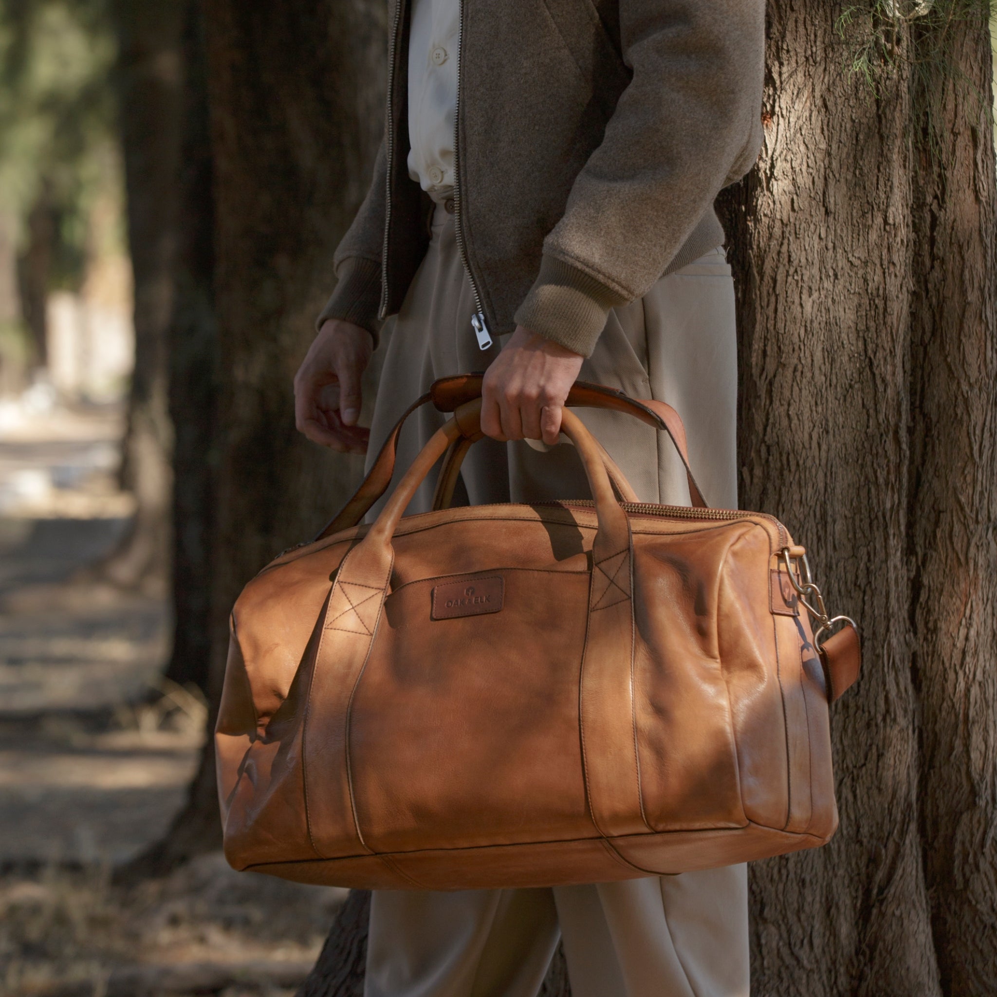 Leather duffel bag made of top-grain leather with smooth zipper, structured body, interior pockets, and adjustable strap
