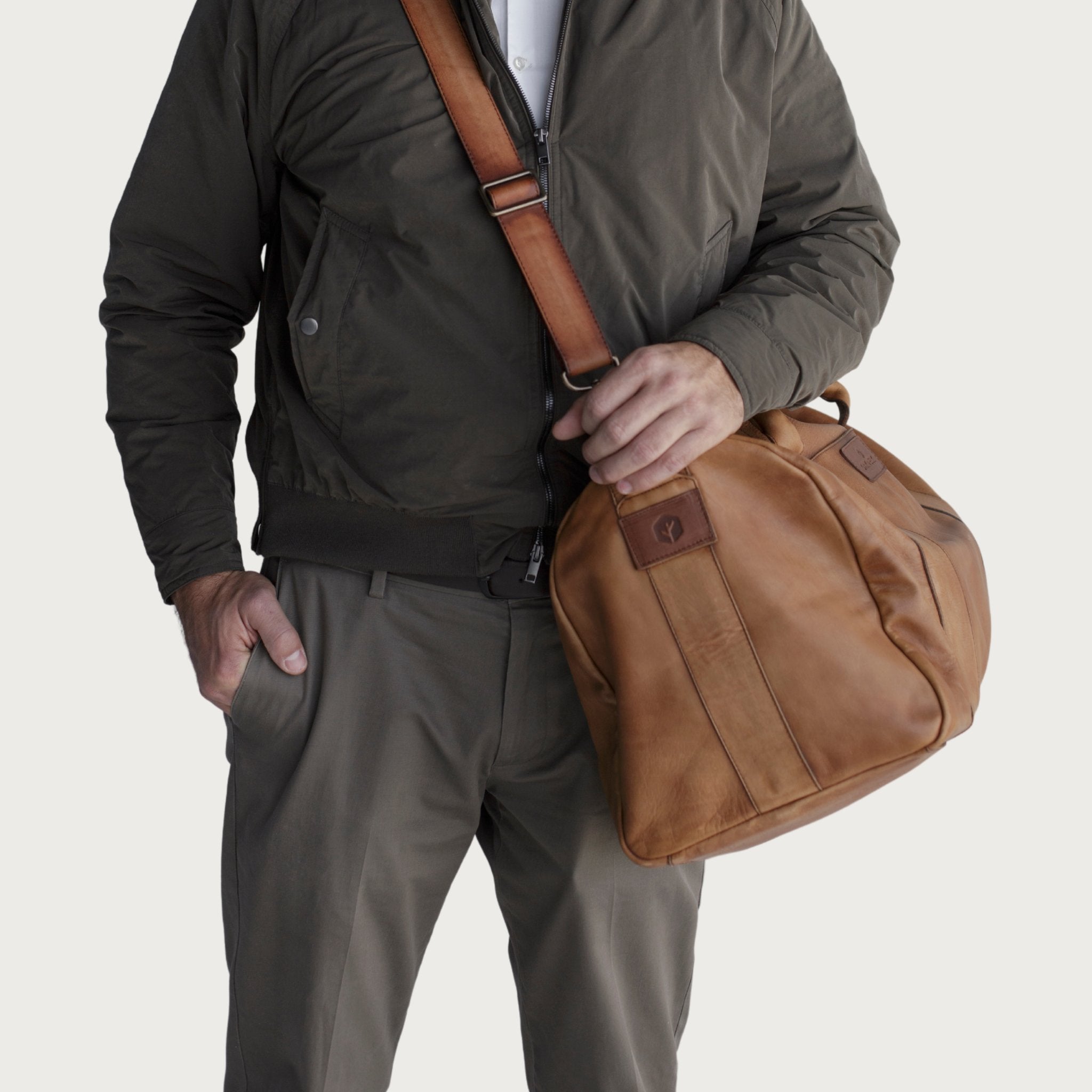Leather duffel bag made of top-grain leather with smooth zipper, structured body, interior pockets, and adjustable strap