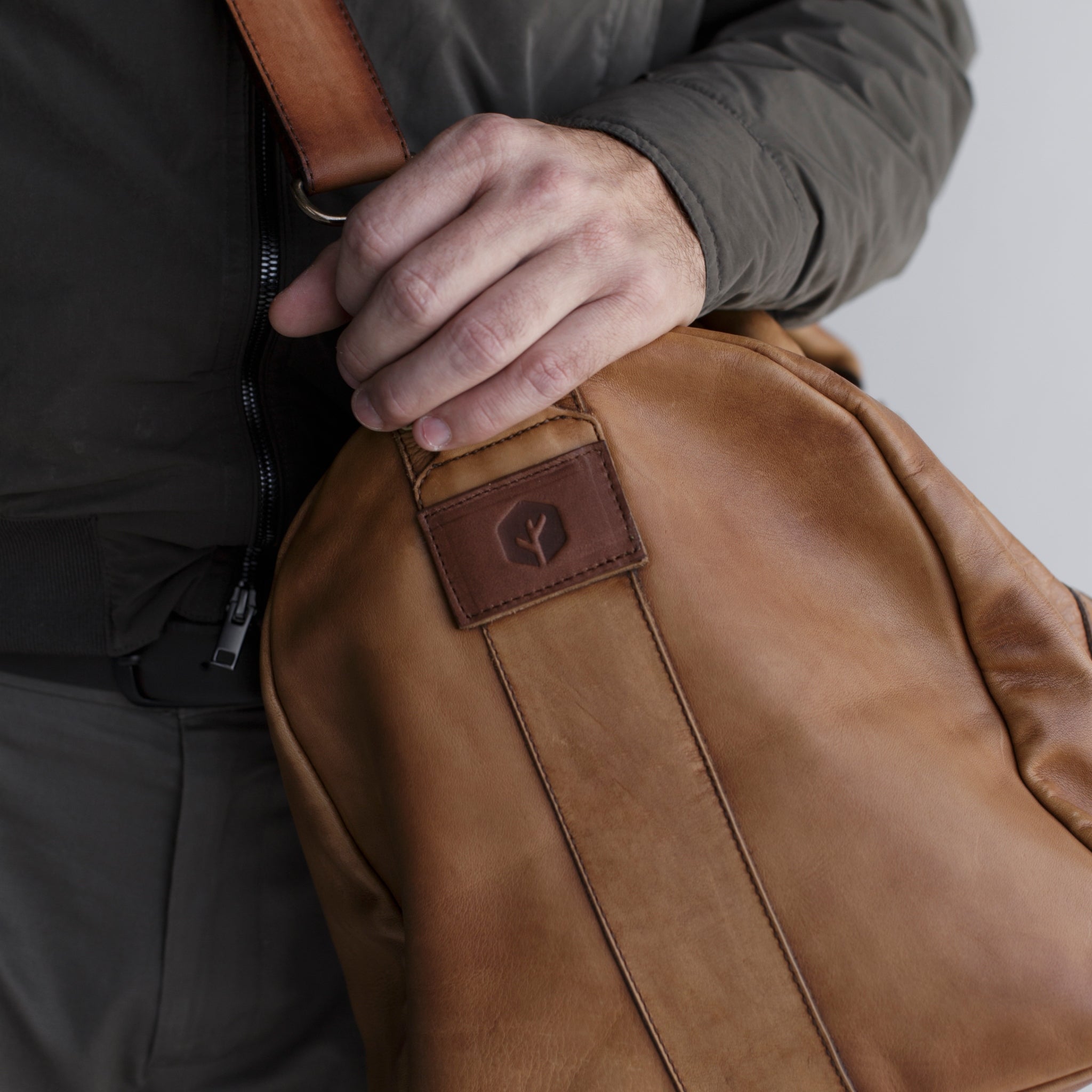 Leather duffel bag made of top-grain leather with smooth zipper, structured body, interior pockets, and adjustable strap