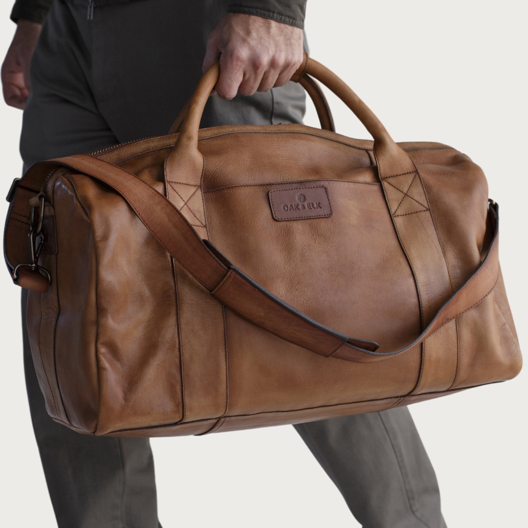 Leather duffel bag made of top-grain leather with smooth zipper, structured body, interior pockets, and adjustable strap