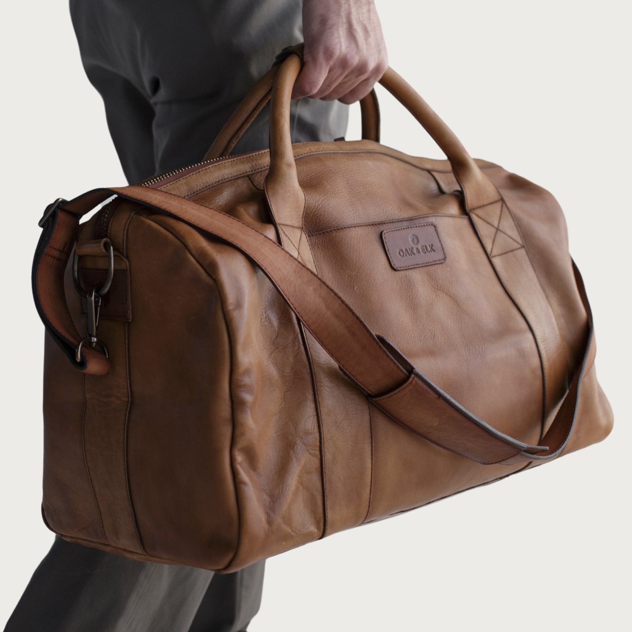 Leather duffel bag made of top-grain leather with smooth zipper, structured body, interior pockets, and adjustable strap