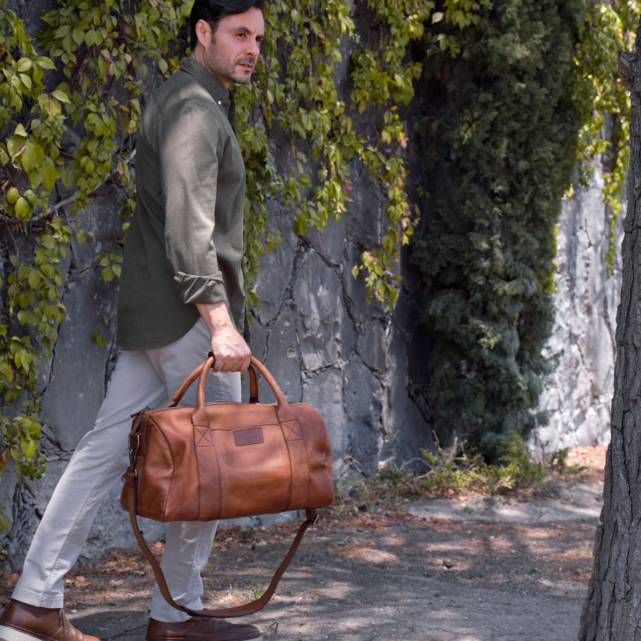 Leather duffel bag made of top-grain leather with smooth zipper, structured body, interior pockets, and adjustable strap