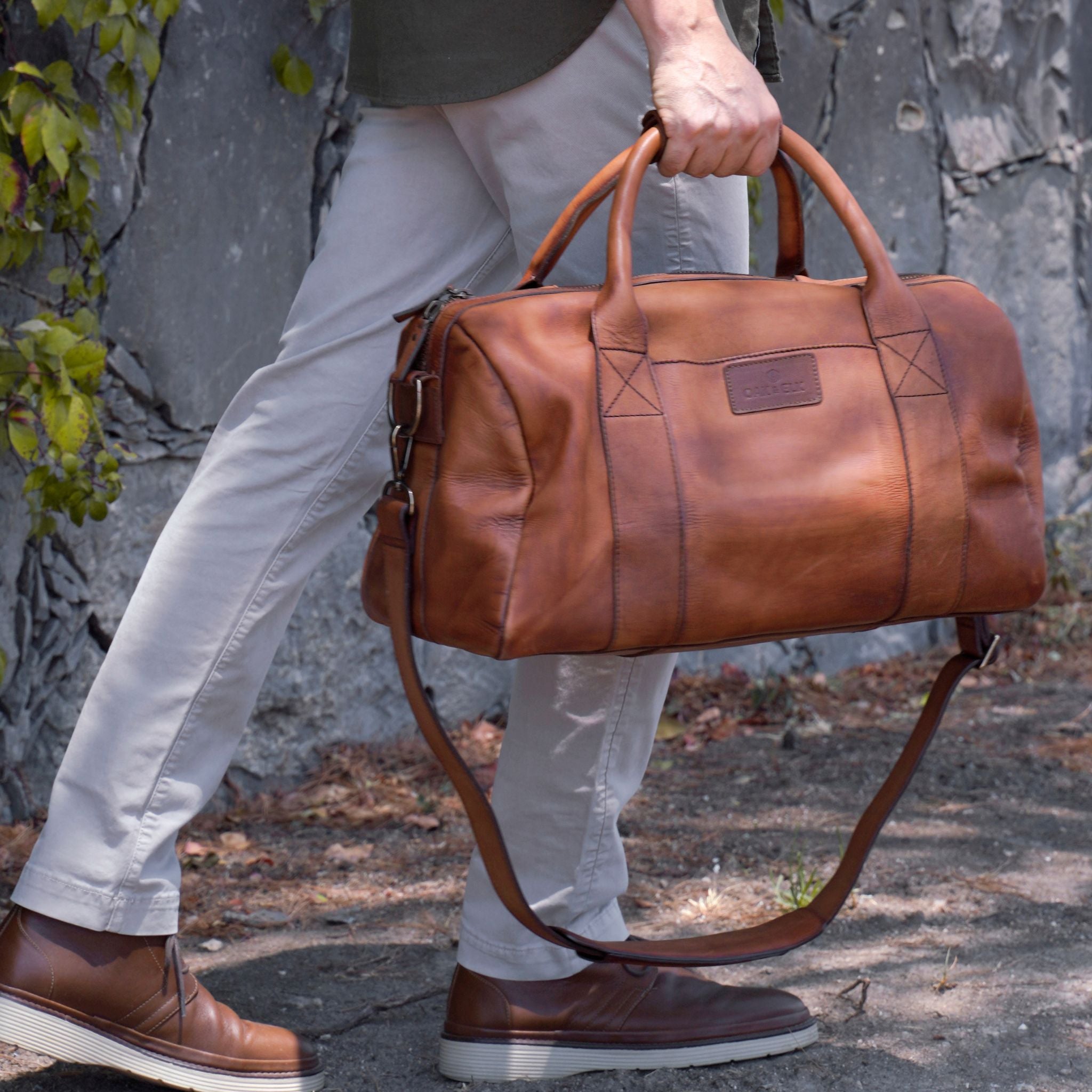 Leather duffel bag made of top-grain leather with smooth zipper, structured body, interior pockets, and adjustable strap