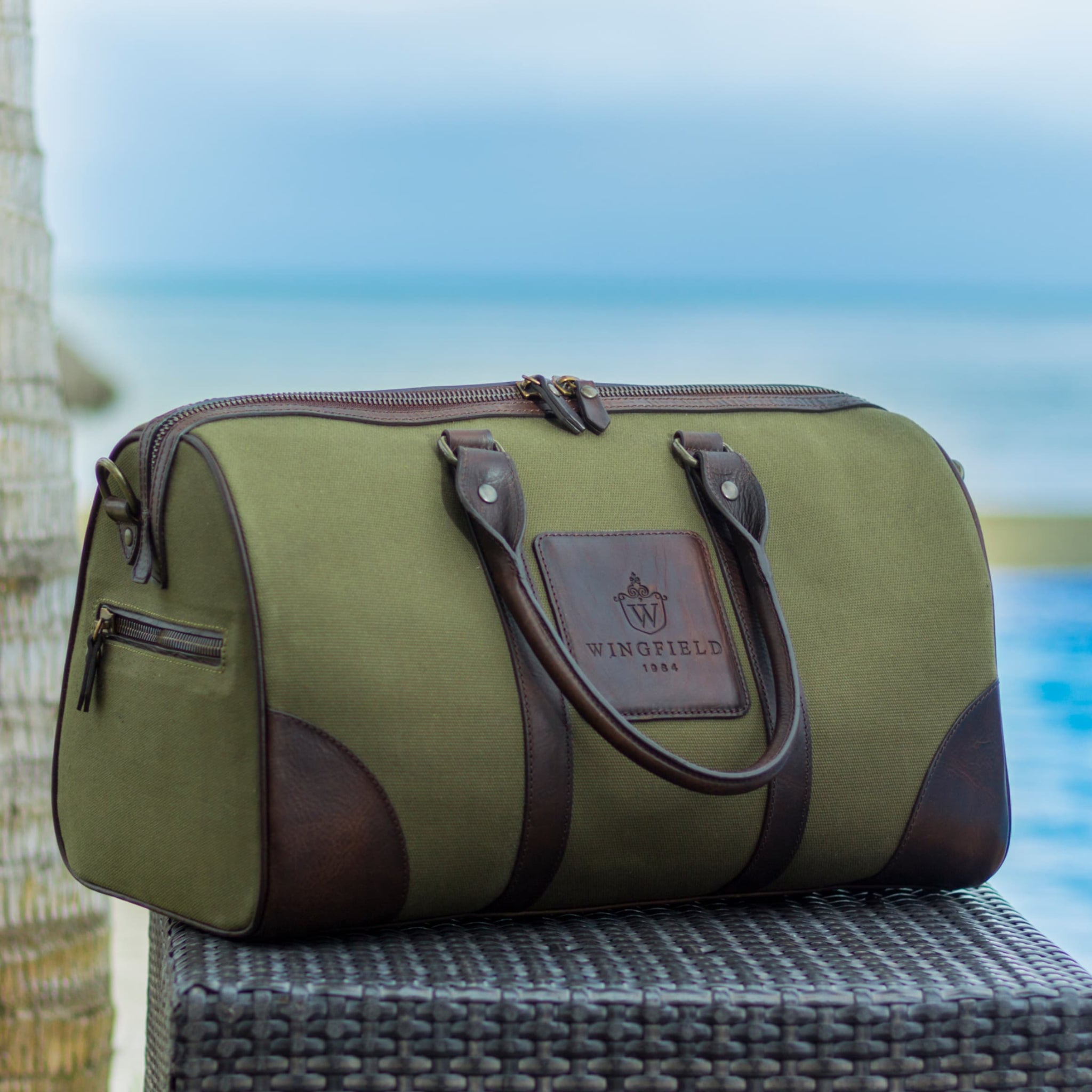 Compact canvas and leather duffel bag with top handles, adjustable shoulder strap, leather accents, zip closure travel ready