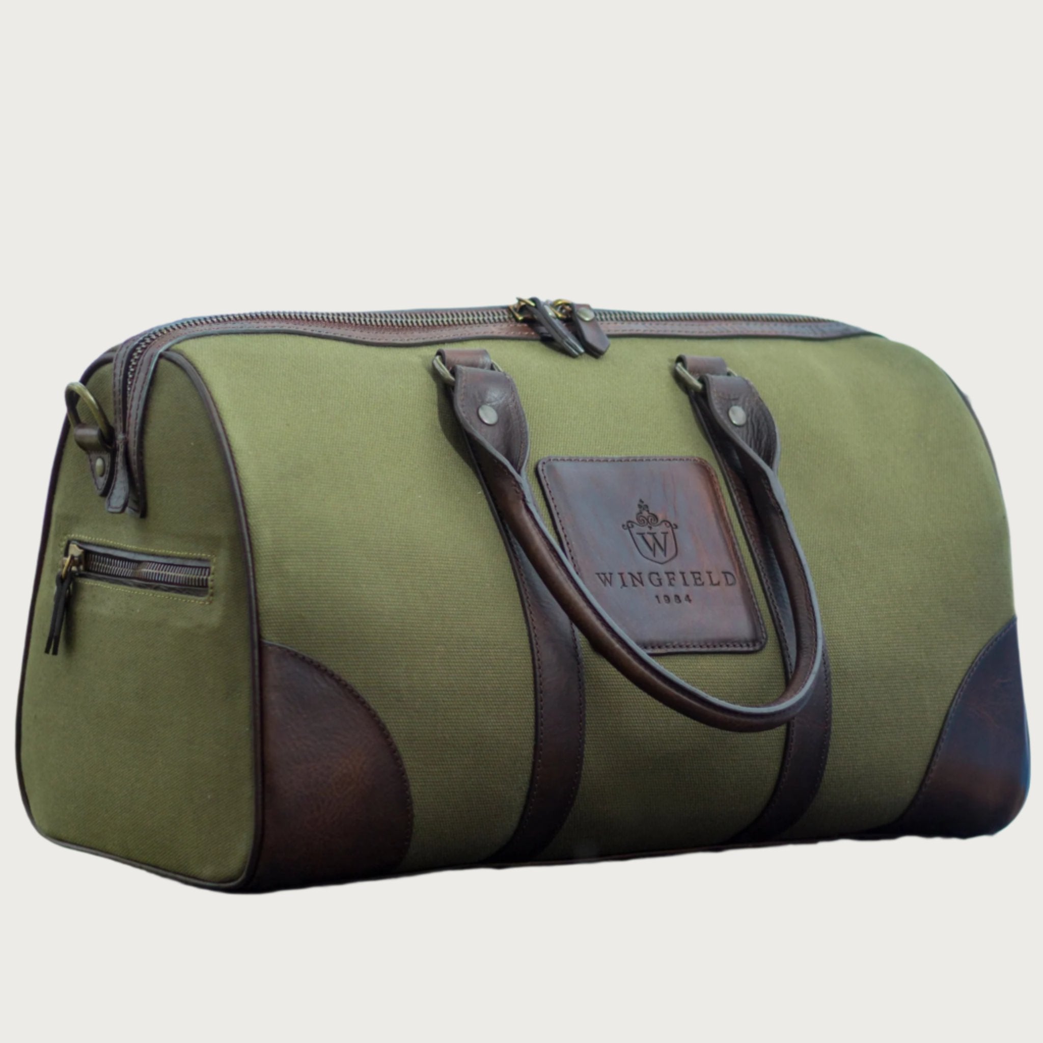 Compact canvas and leather duffel bag with top handles, adjustable shoulder strap, leather accents, zip closure travel ready