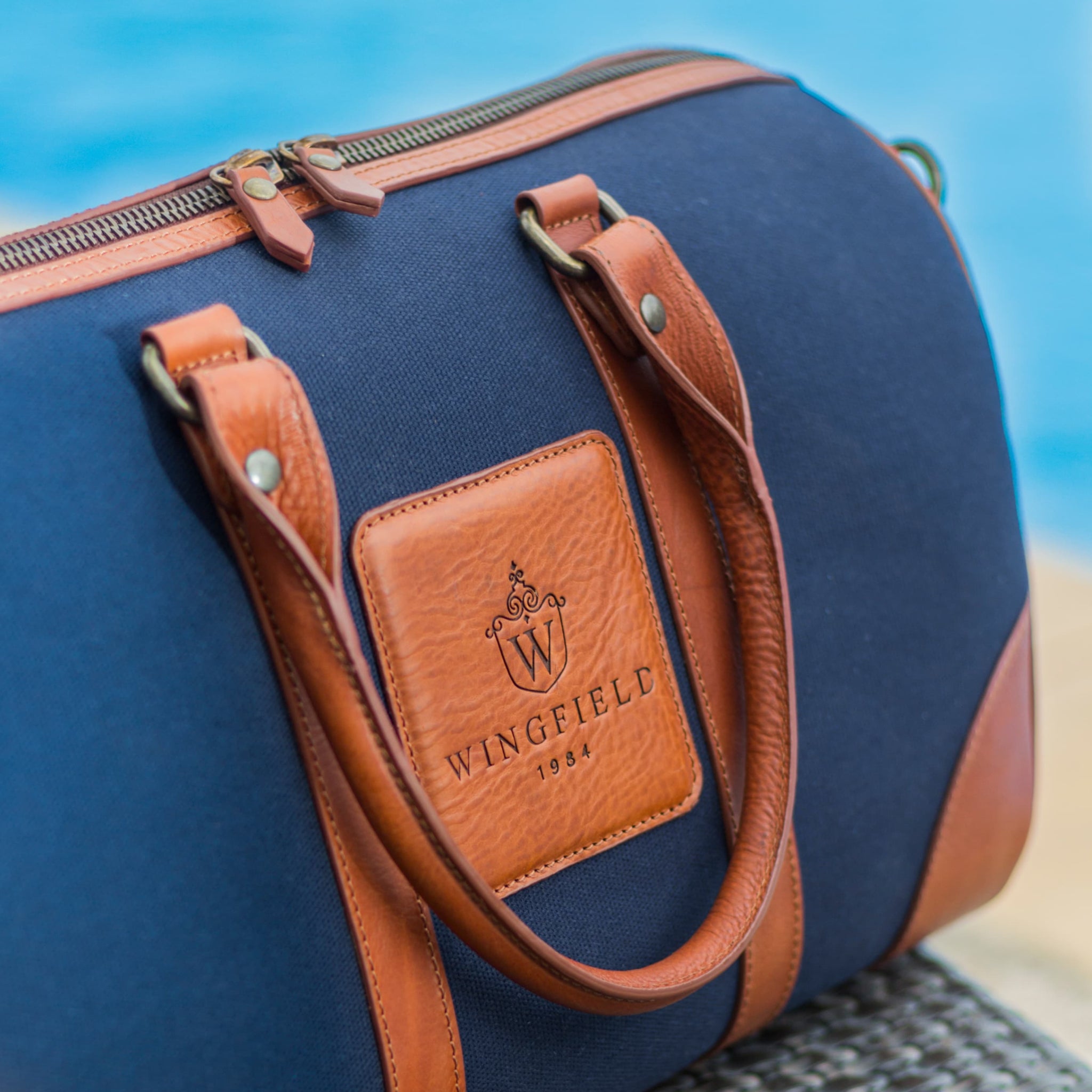 Compact canvas and leather duffel bag with top handles, adjustable shoulder strap, leather accents, zip closure travel ready