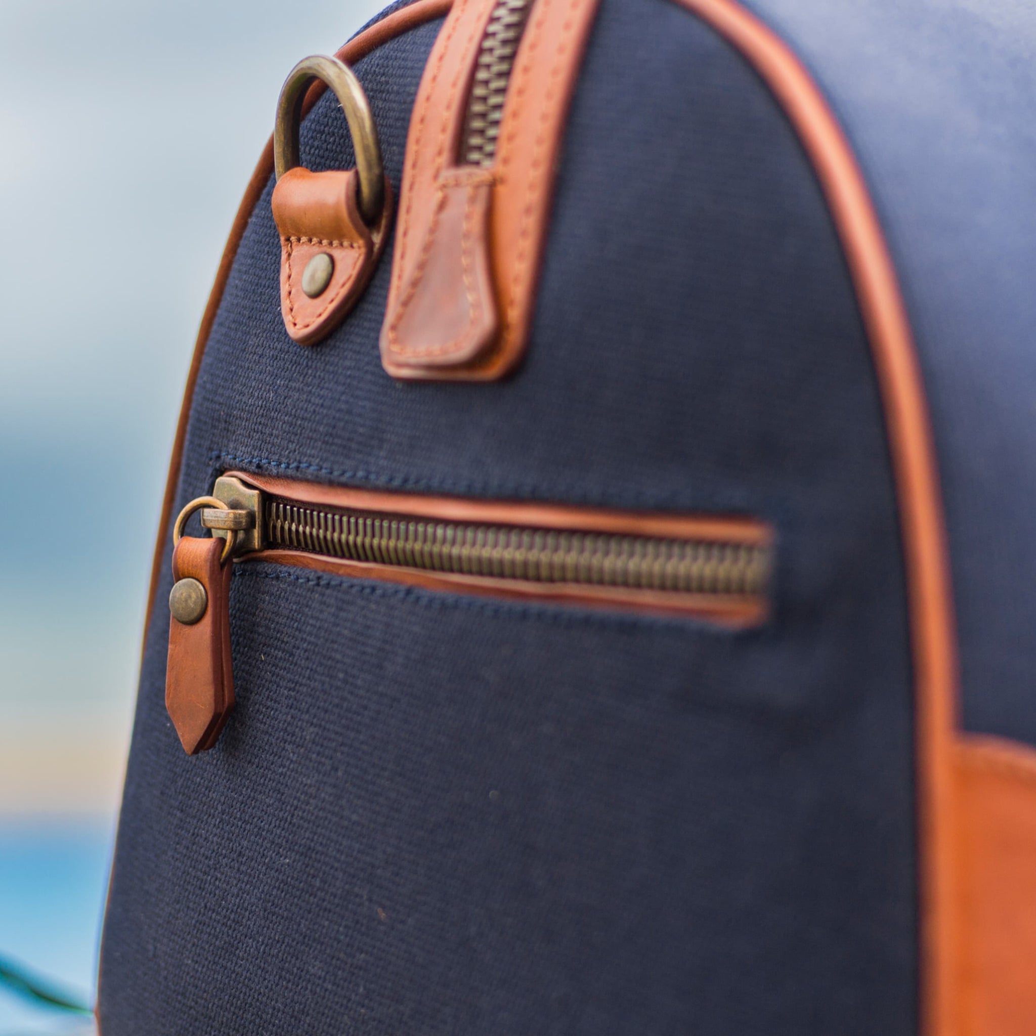 Compact canvas and leather duffel bag with top handles, adjustable shoulder strap, leather accents, zip closure travel ready