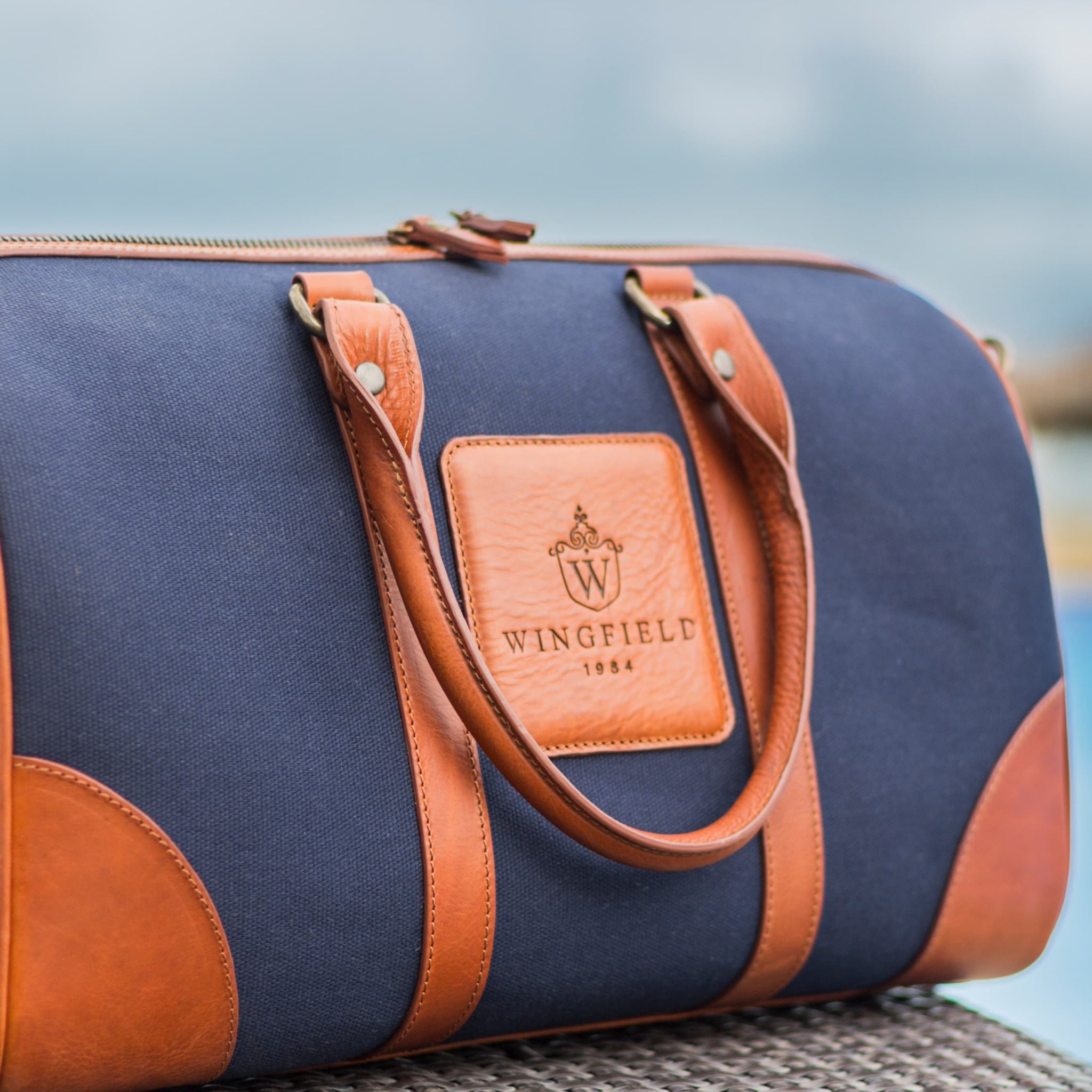 Compact canvas and leather duffel bag with top handles, adjustable shoulder strap, leather accents, zip closure travel ready