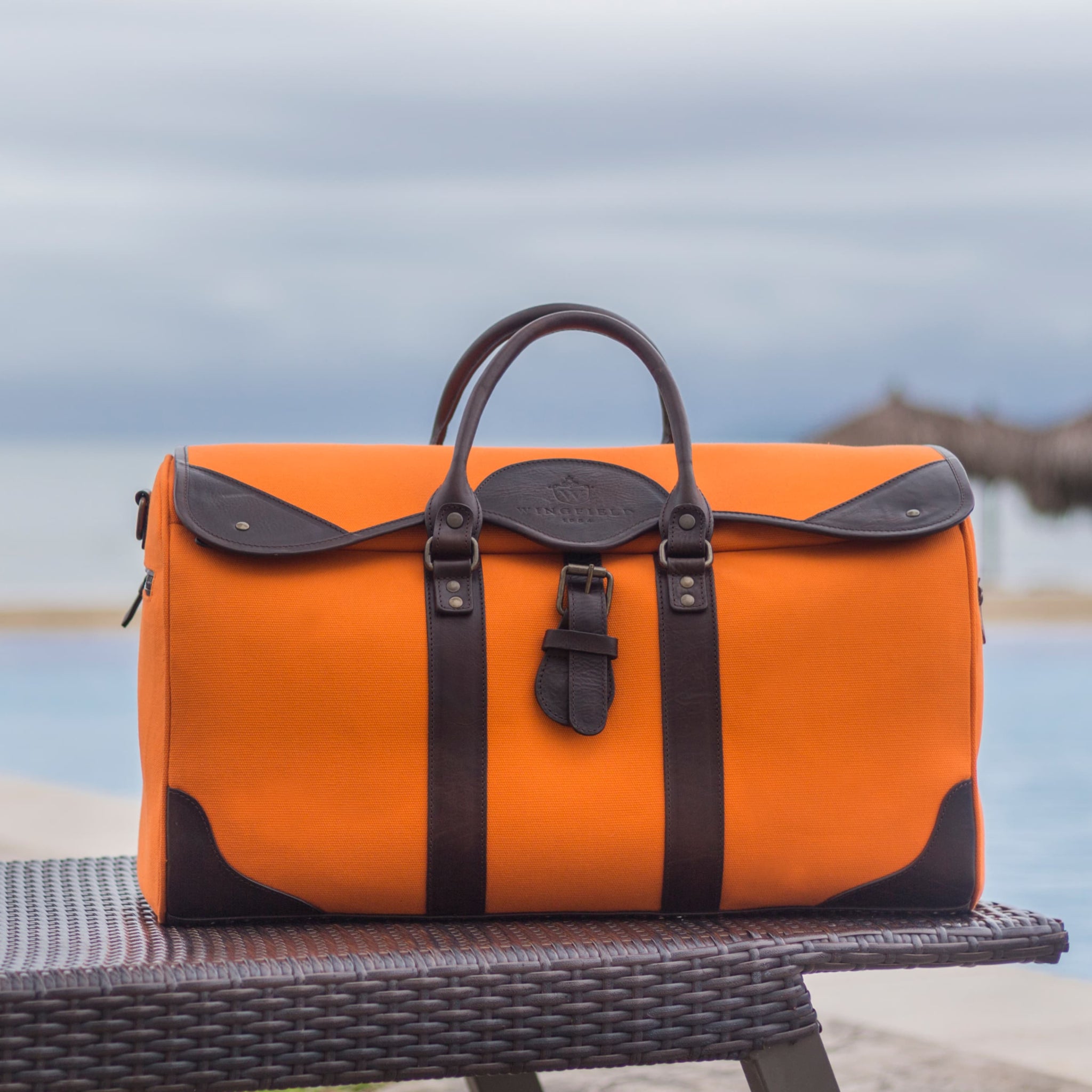 Large canvas and leather duffel bag with top handles, adjustable shoulder strap, leather trim, and zip closure, for travel