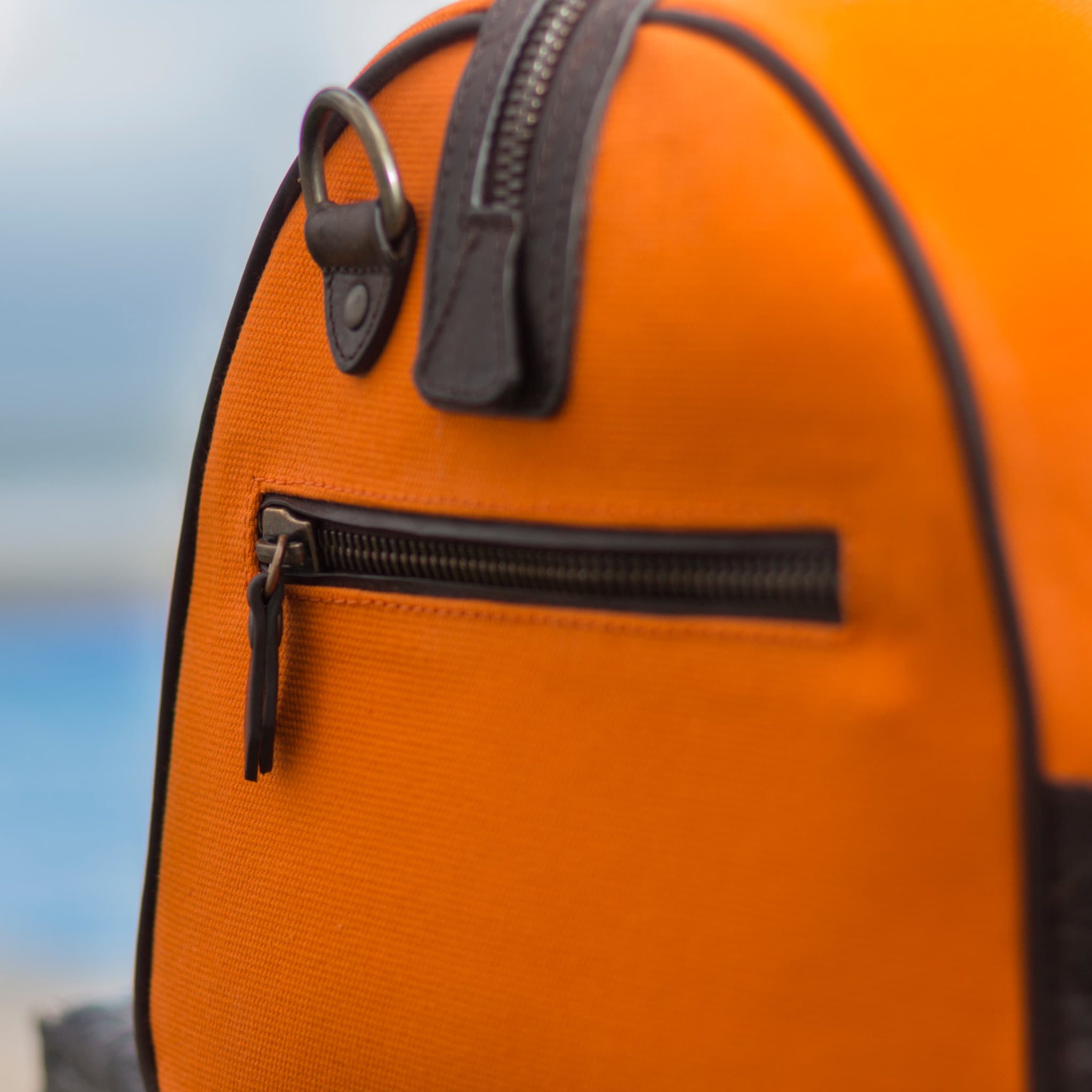 Compact canvas and leather duffel bag with top handles, adjustable shoulder strap, leather accents, zip closure travel ready