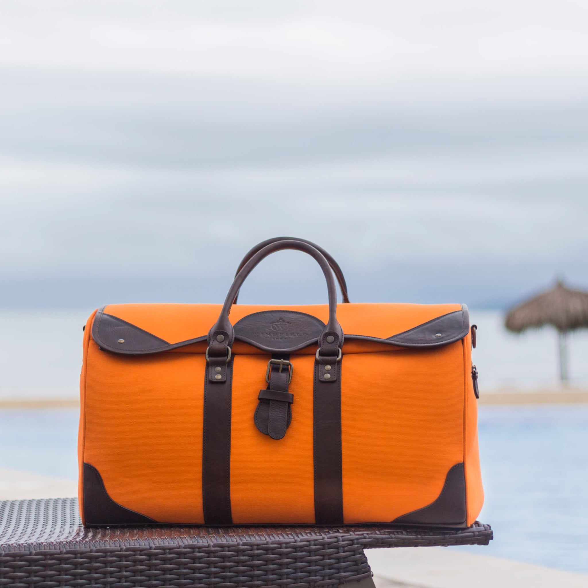 Large canvas and leather duffel bag with top handles, adjustable shoulder strap, leather trim, and zip closure, for travel