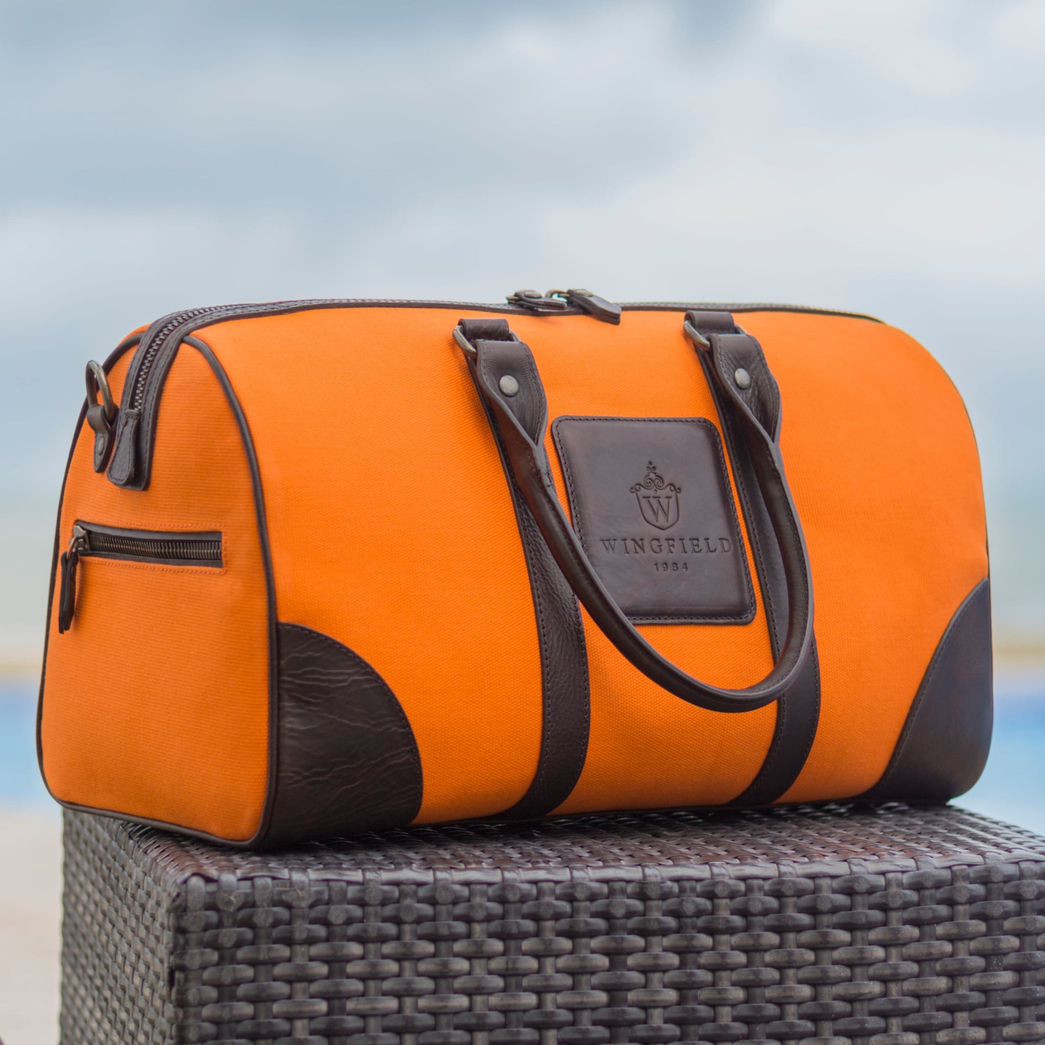 Compact canvas and leather duffel bag with top handles, adjustable shoulder strap, leather accents, zip closure travel ready