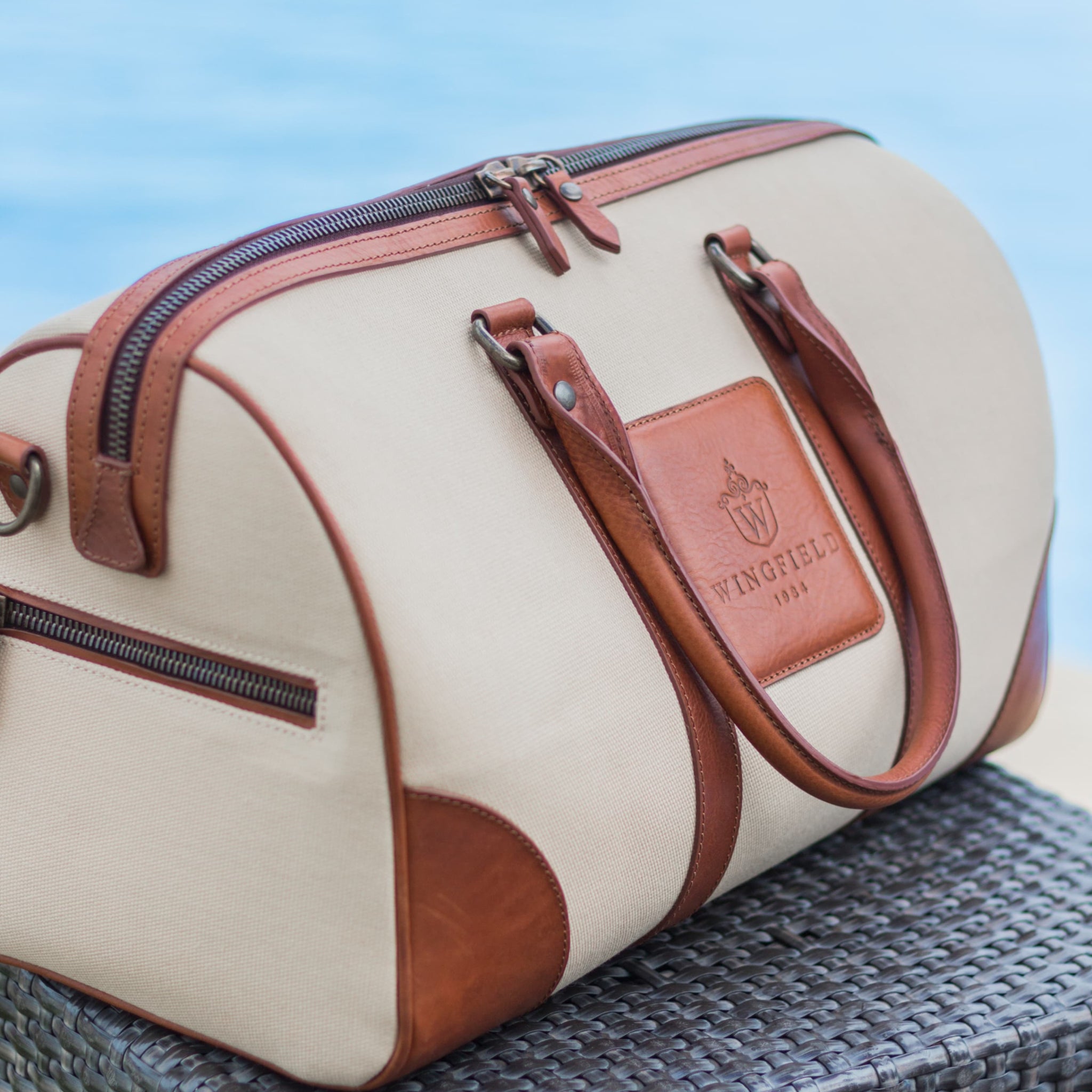 Compact canvas and leather duffel bag with top handles, adjustable shoulder strap, leather accents, zip closure travel ready