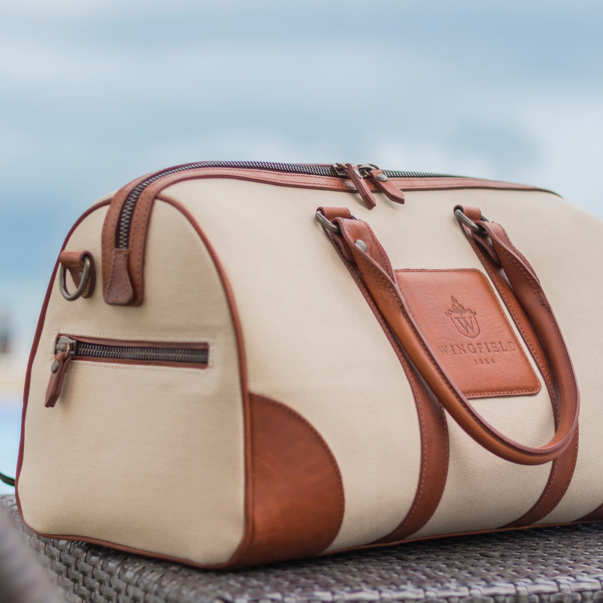 Compact canvas and leather duffel bag with top handles, adjustable shoulder strap, leather accents, zip closure travel ready