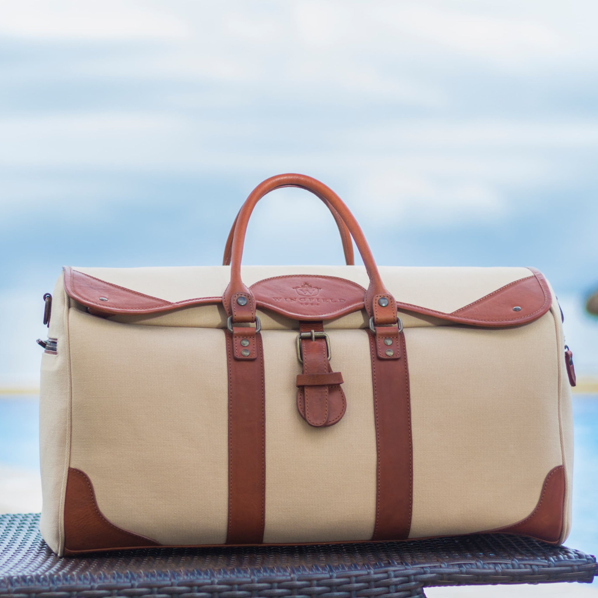 Large canvas and leather duffel bag with top handles, adjustable shoulder strap, leather trim, and zip closure, for travel