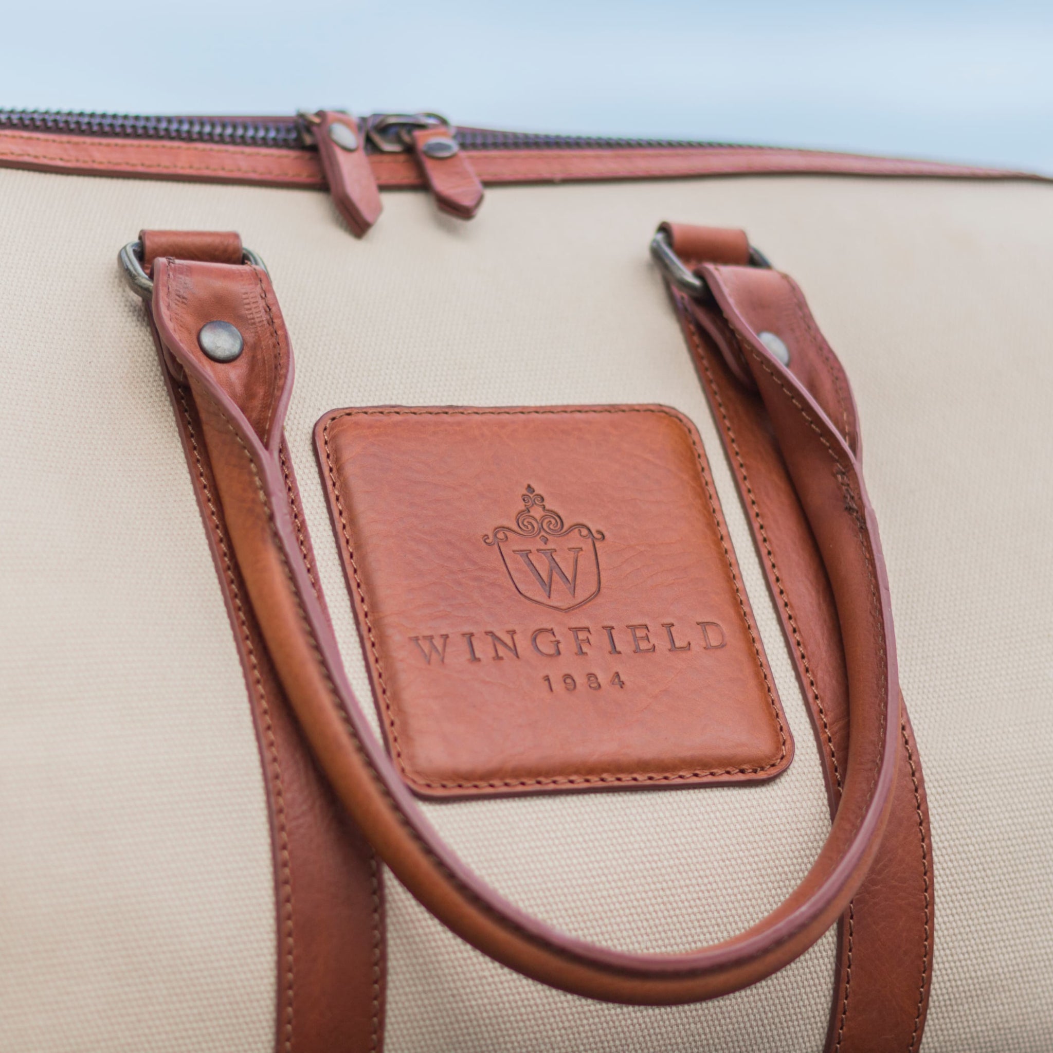 Compact canvas and leather duffel bag with top handles, adjustable shoulder strap, leather accents, zip closure travel ready